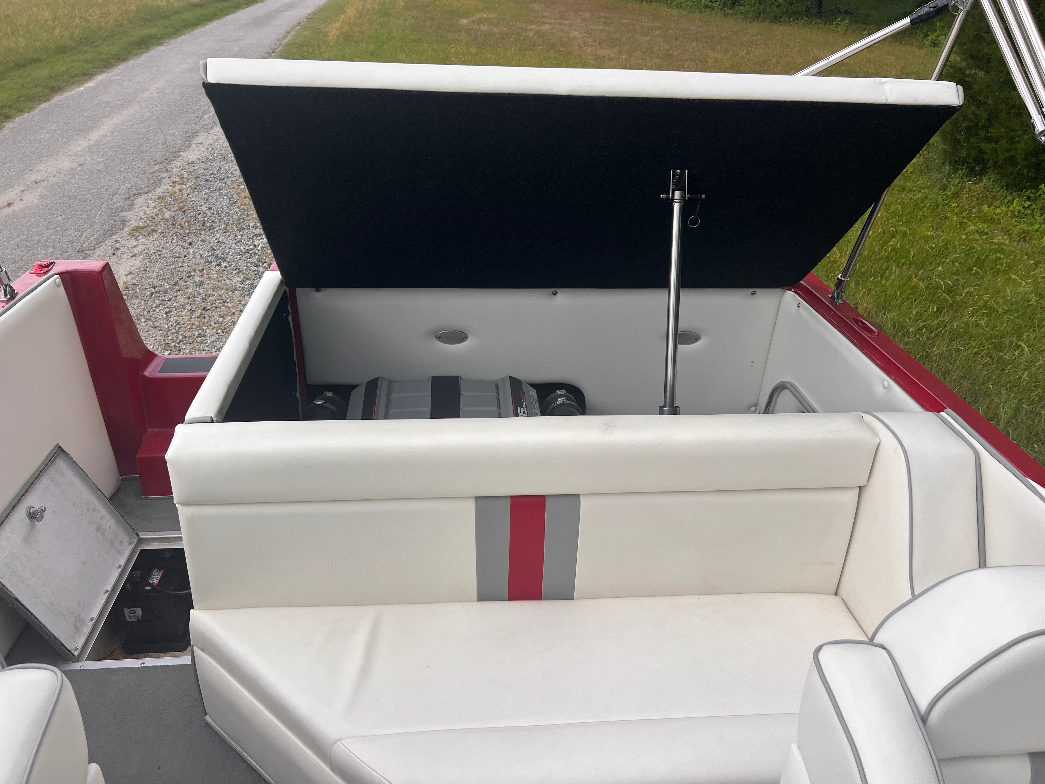 The image shows the interior of a boat with white seating and an open engine compartment.