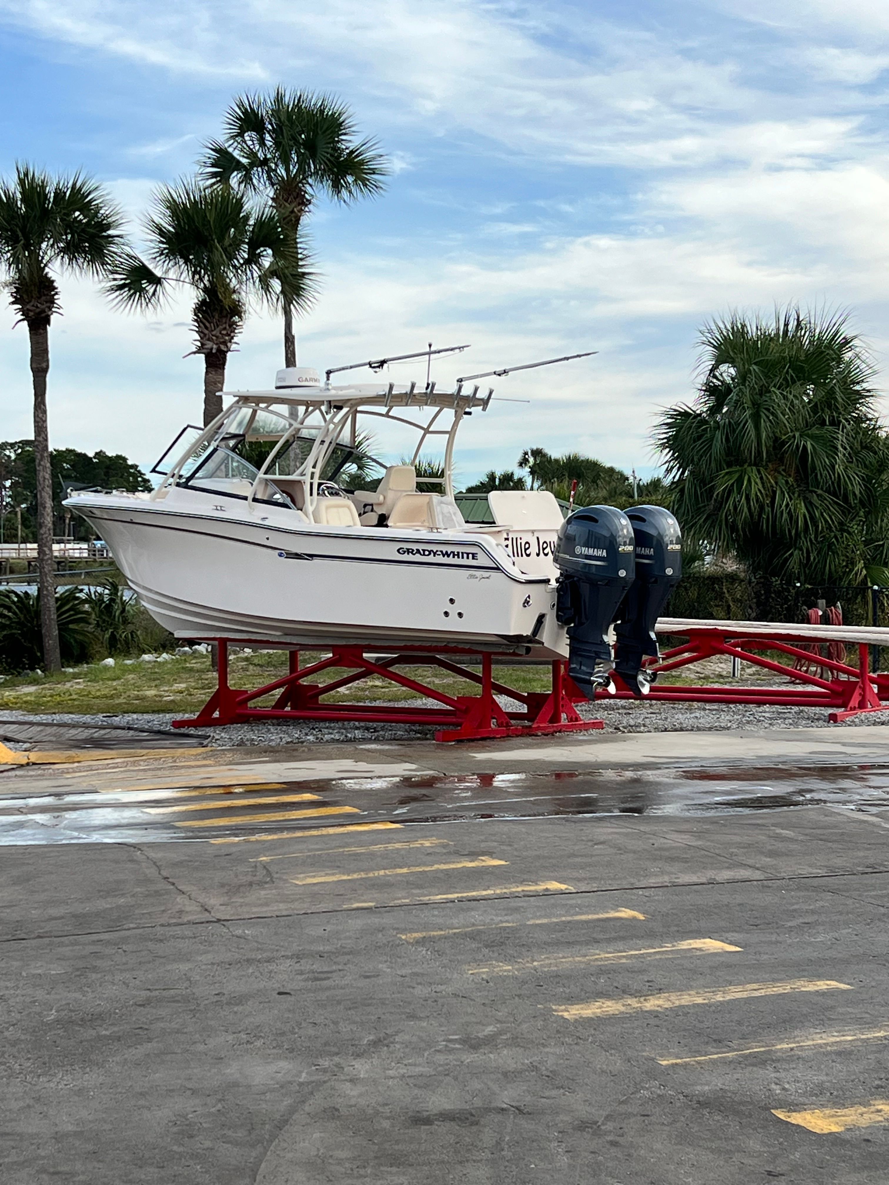A 2015 Grady-White Freedom 275 boat on a red trailer, surrounded by palm trees.