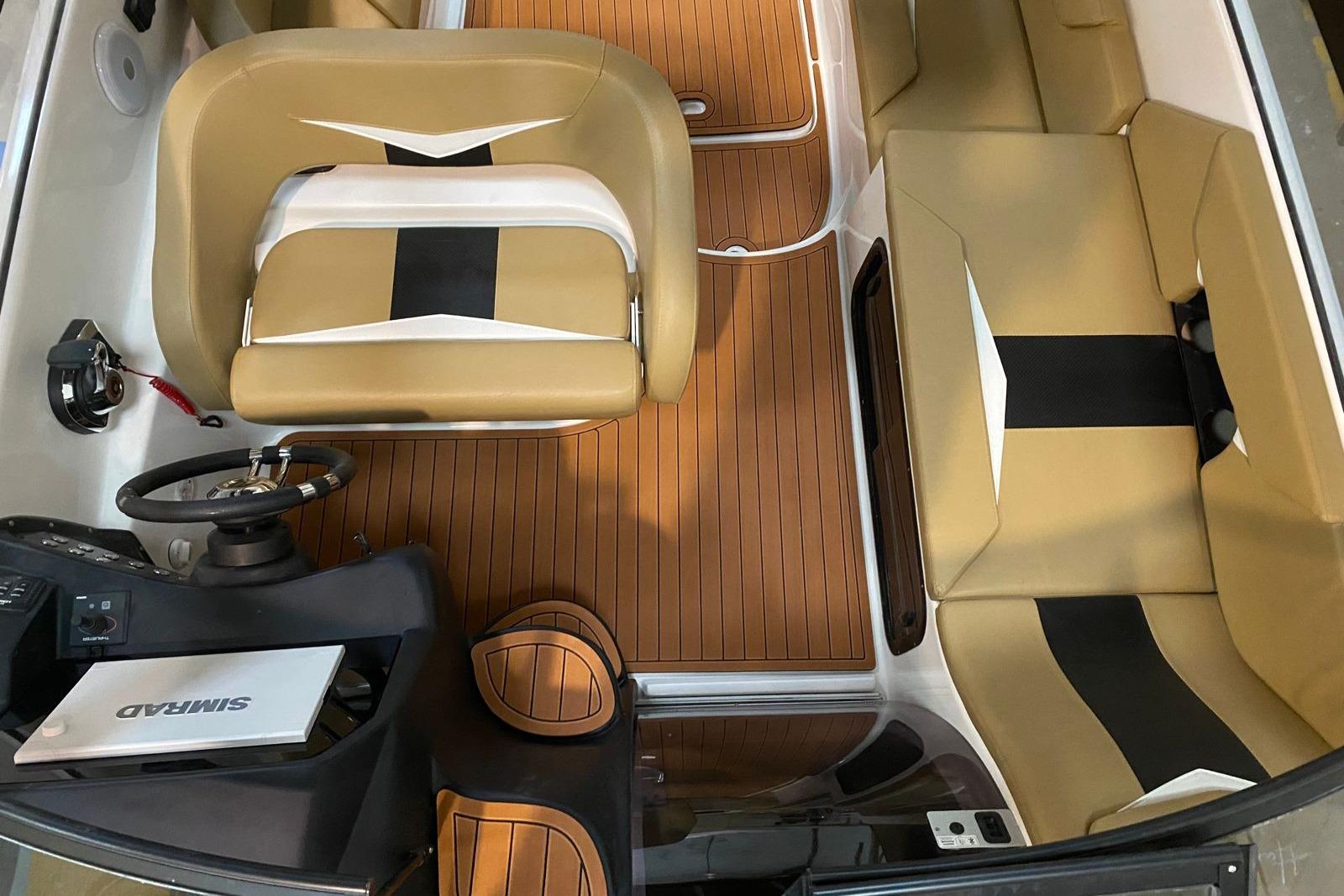 Interior of 2026 Hanover 305 boat with tan seating and wood flooring.