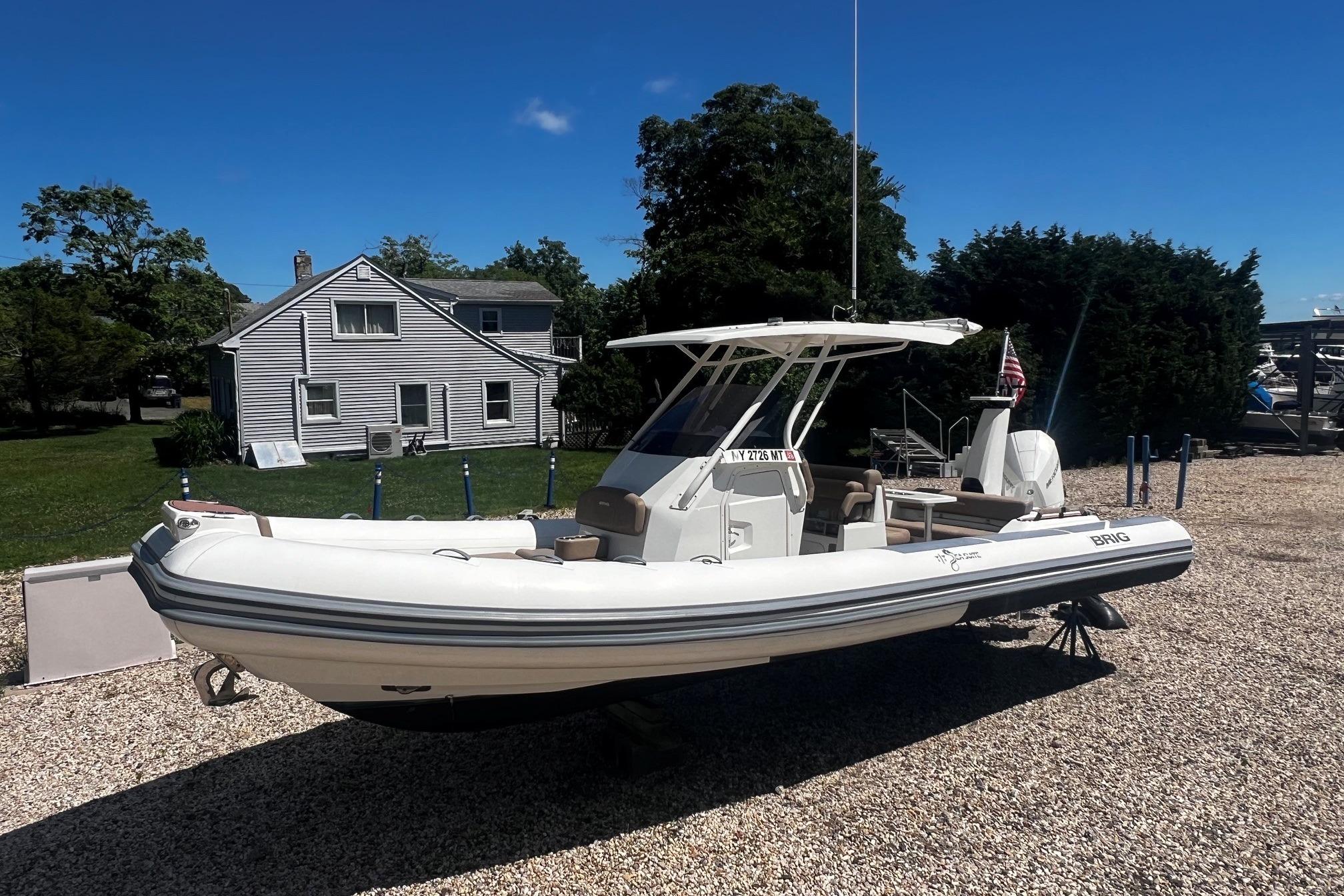 2022 Brig Eagle 8 boat on gravel, near a house and trees, under clear blue sky.