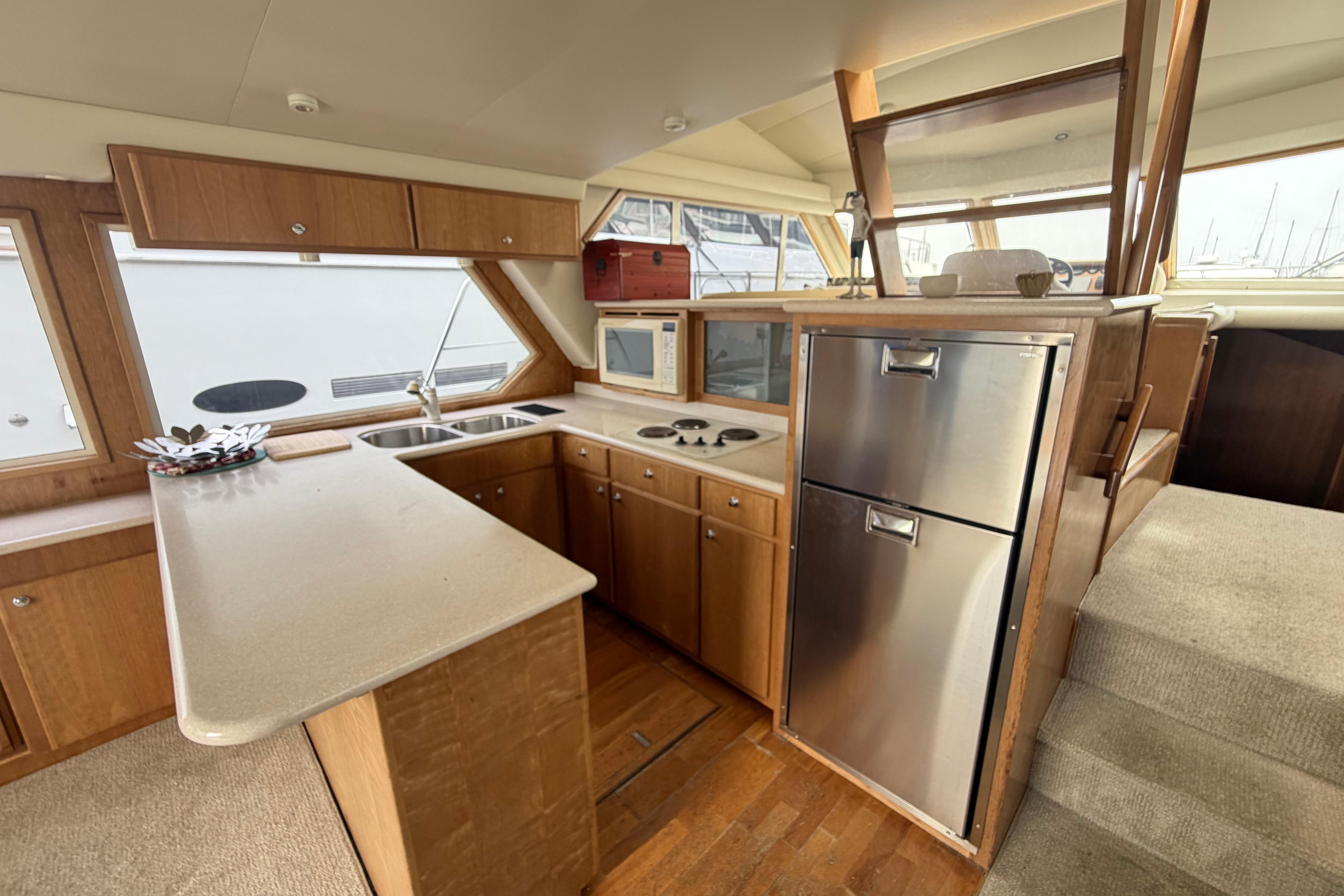 2005 Navigator 53 Pilot House yacht kitchen with wood cabinetry and stainless steel appliances.