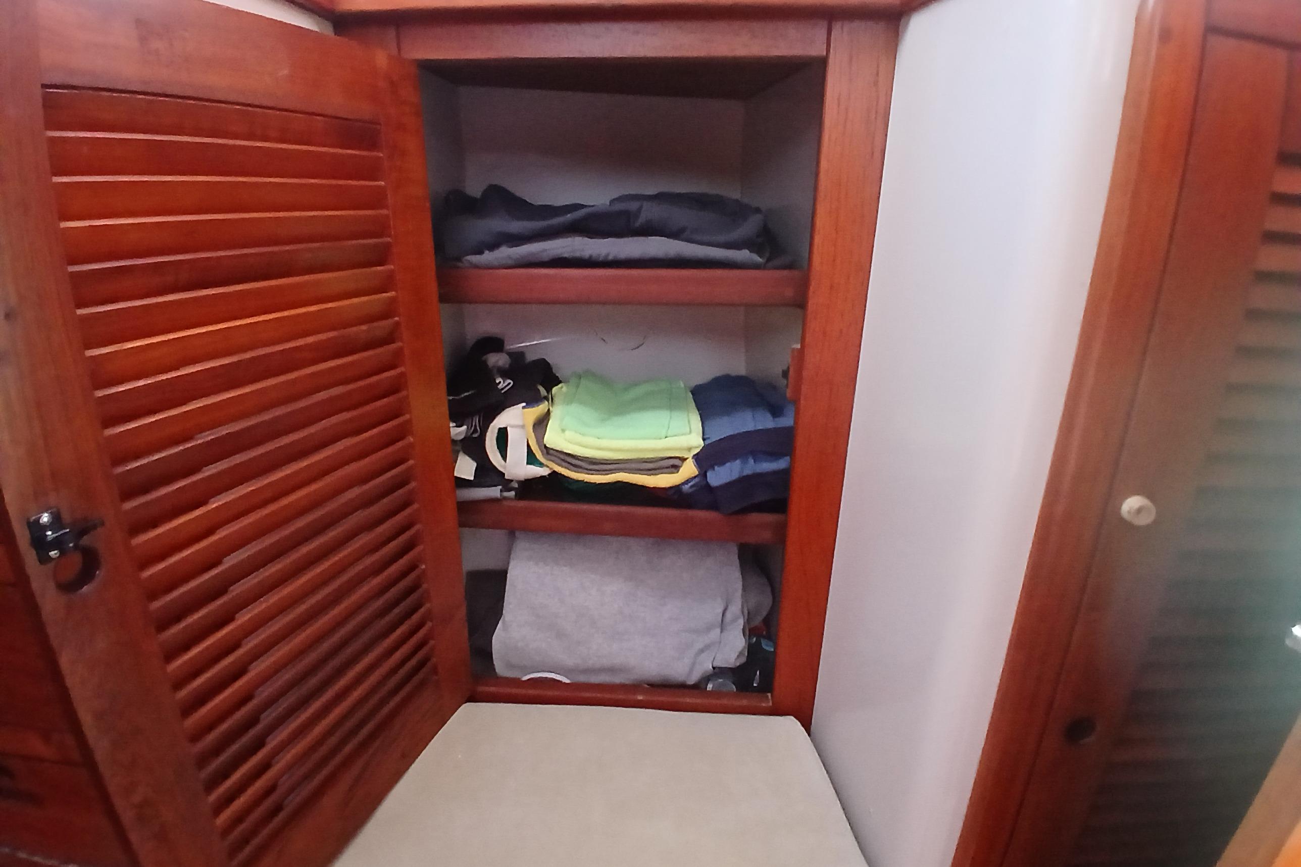 Wooden closet with folded clothes inside a 1995 Catalina 42 MkII sailboat.