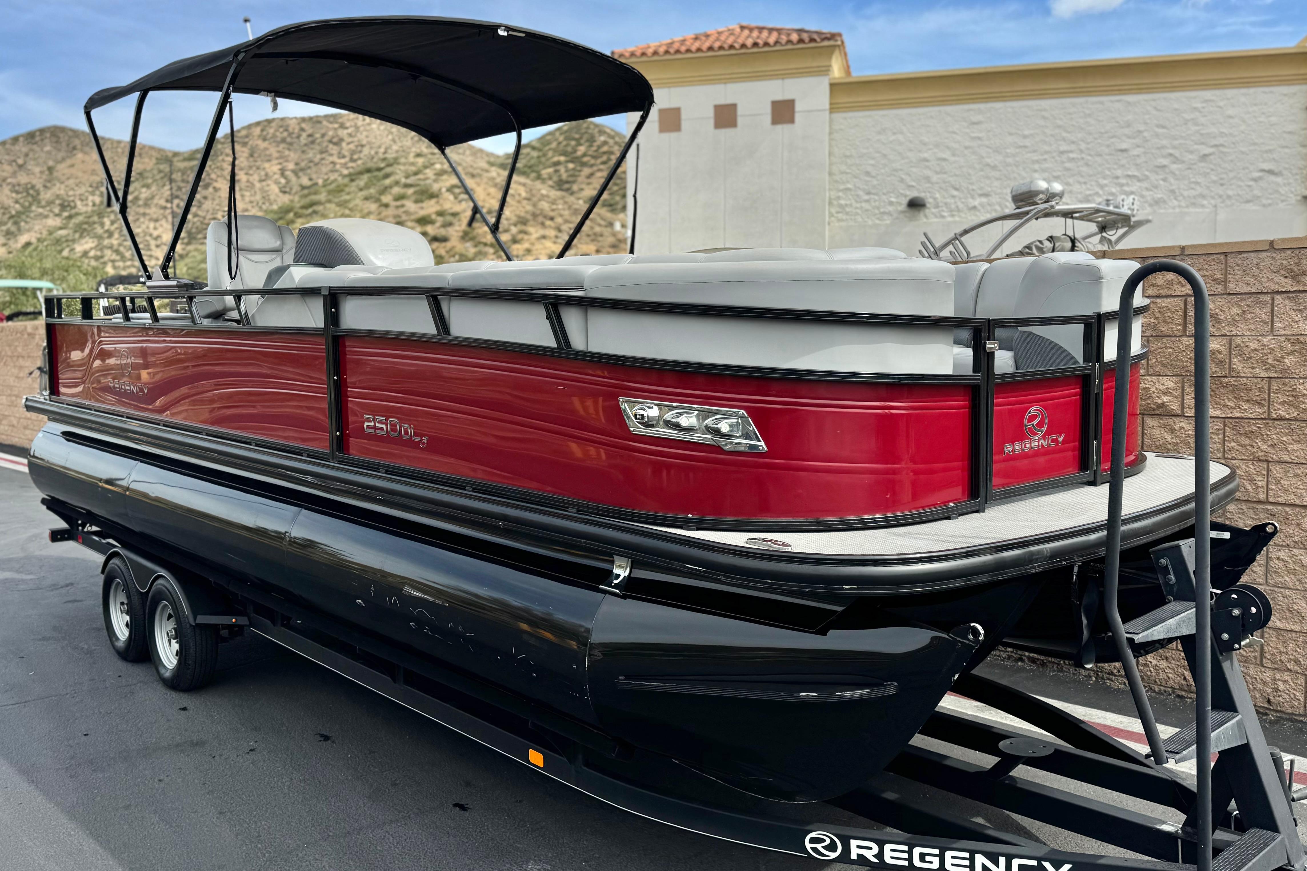 2022 Regency 250 DL3 pontoon boat with red exterior on a trailer.