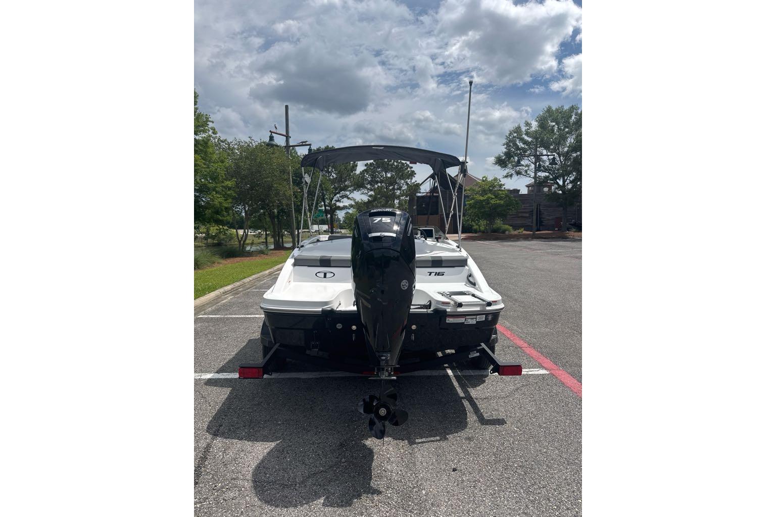 2026 Tahoe T16 boat with outboard motor in parking lot under cloudy sky.
