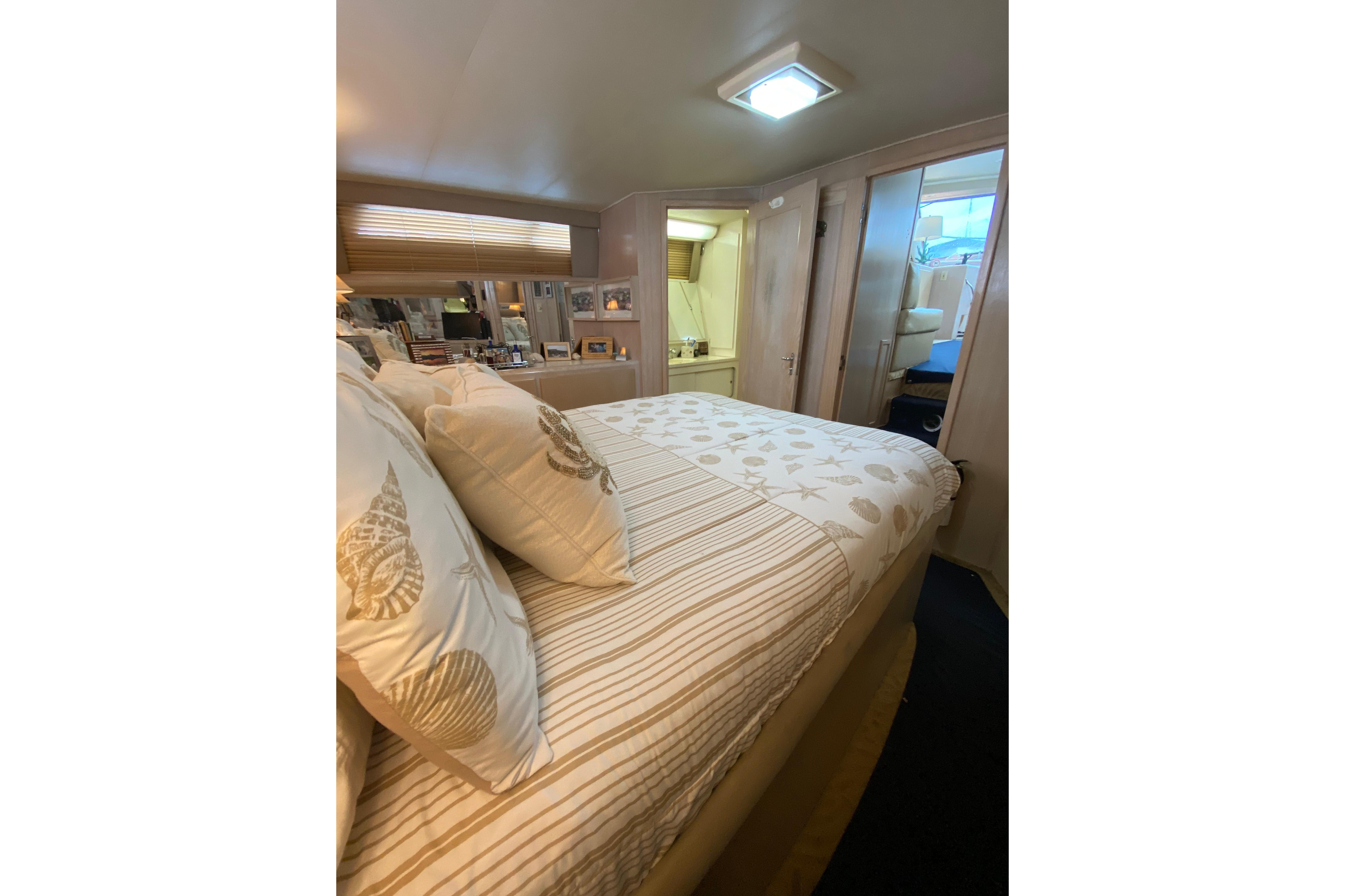 Cozy bedroom interior of 1991 Hatteras 40 Motor Yacht with nautical-themed bedding.