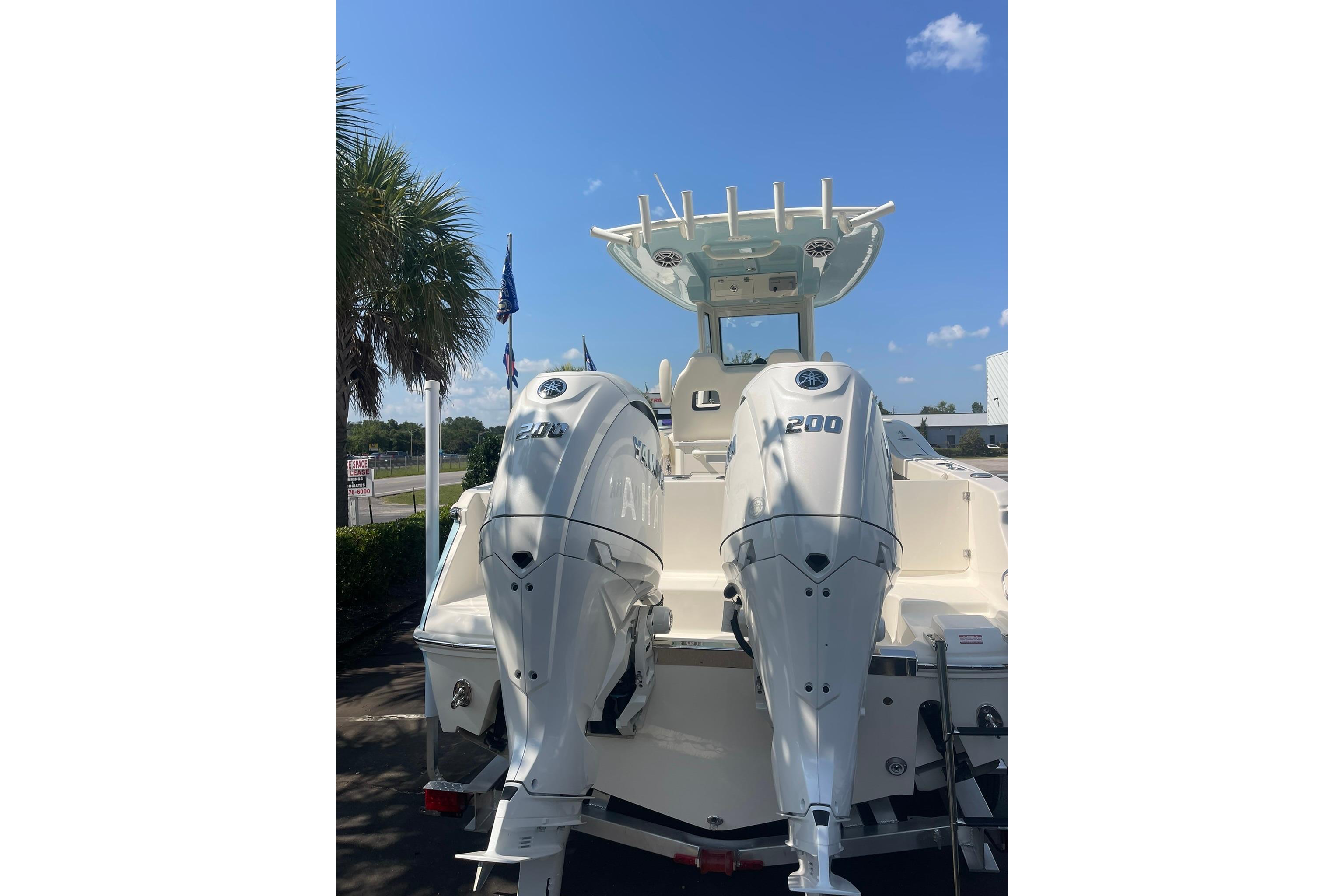 2026 Pioneer 250 Pelagic boat with dual 200 horsepower engines, parked under a clear blue sky.