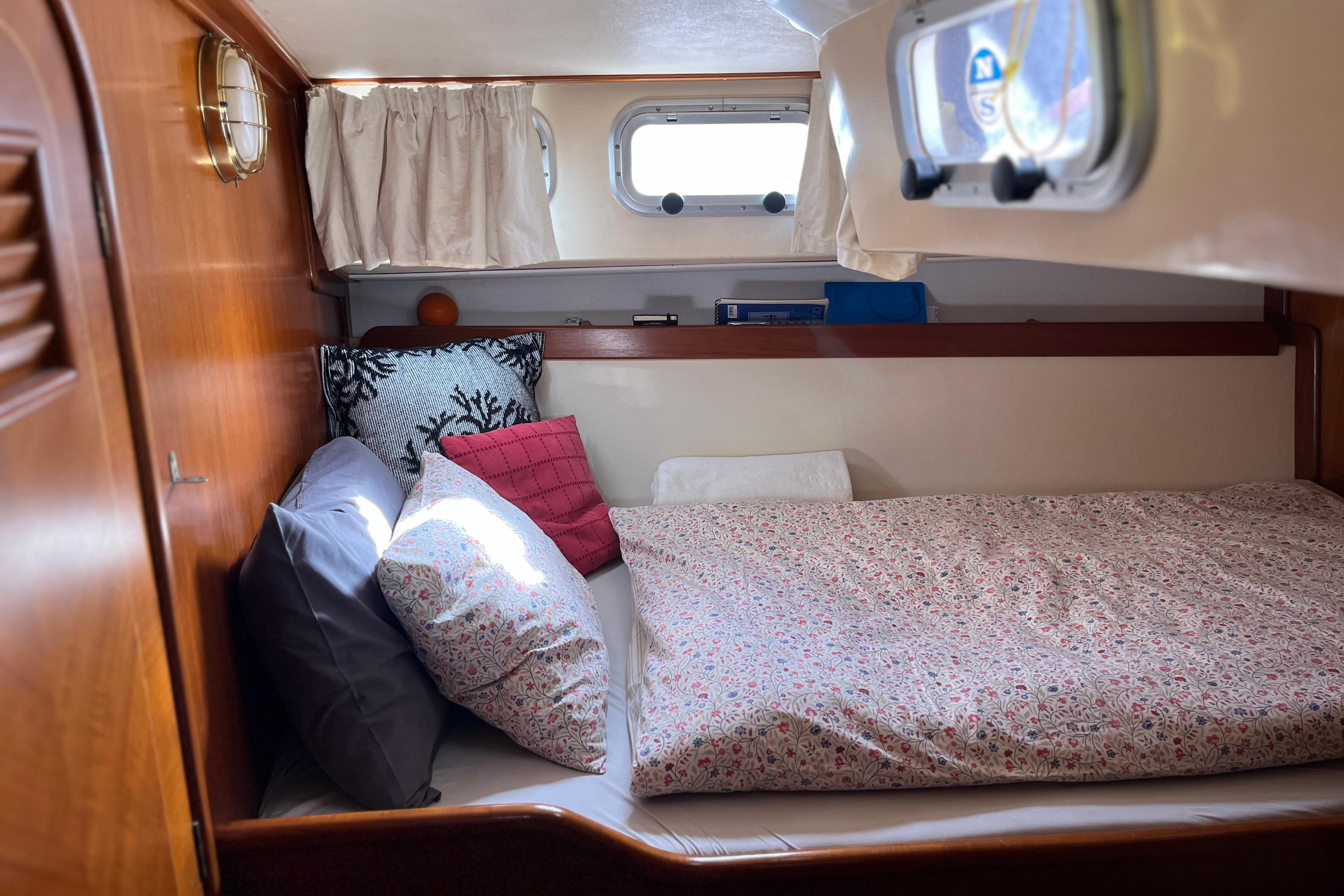 Cozy cabin interior of 1995 Belliure 41 yacht with floral bedding and porthole window.