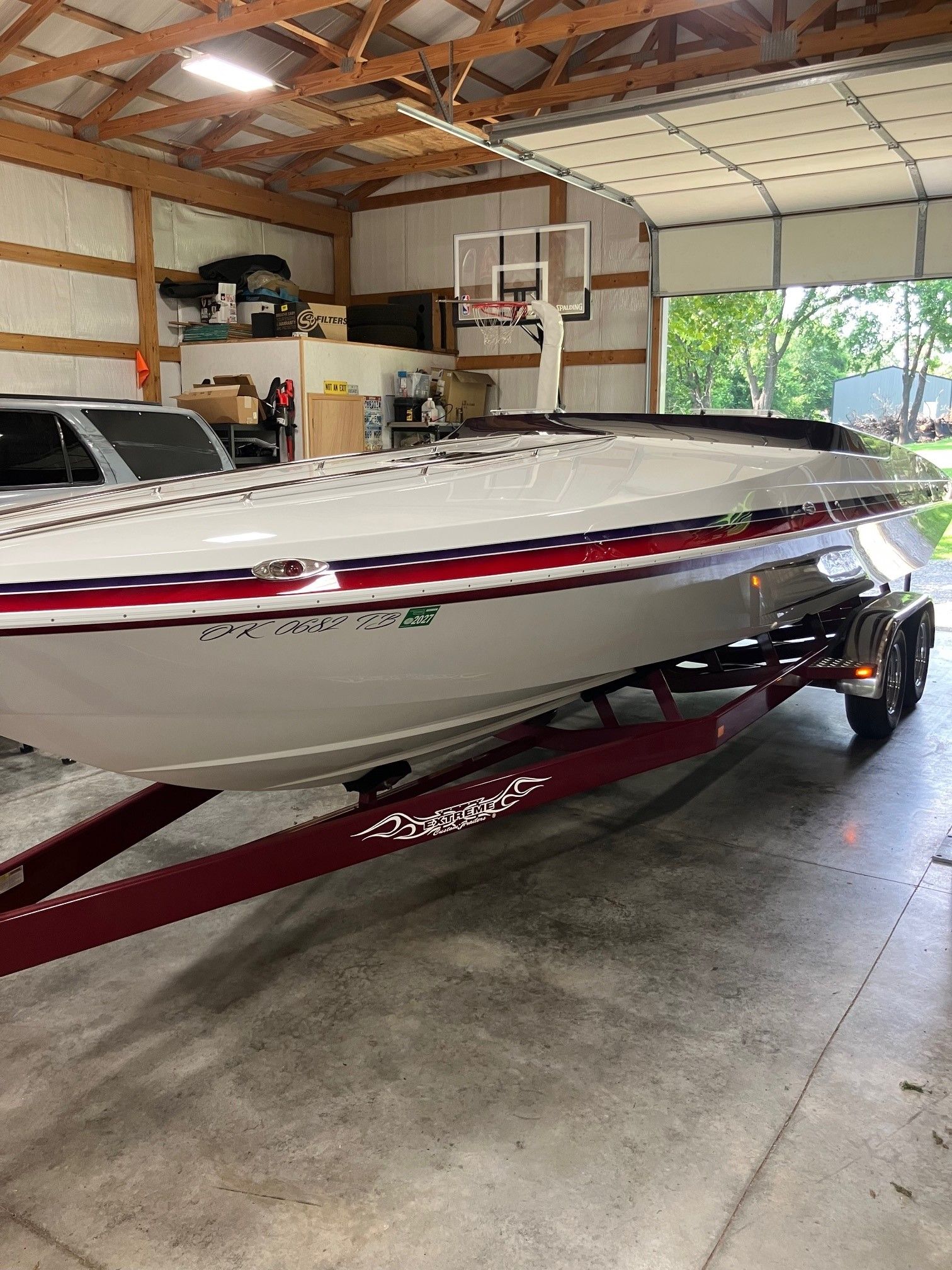 A white boat with red and blue stripes sits on a trailer in a garage.