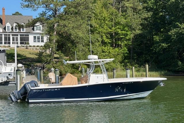 2014 Southport 29 FE boat docked by a lakeside house with lush greenery.