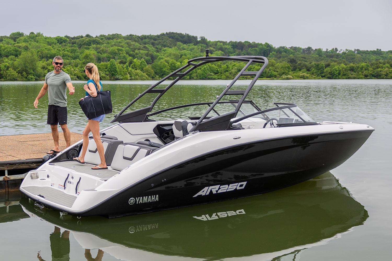 Manufacturer Provided Image: 2026 Yamaha AR250 boat docked on a serene lake with two people nearby.