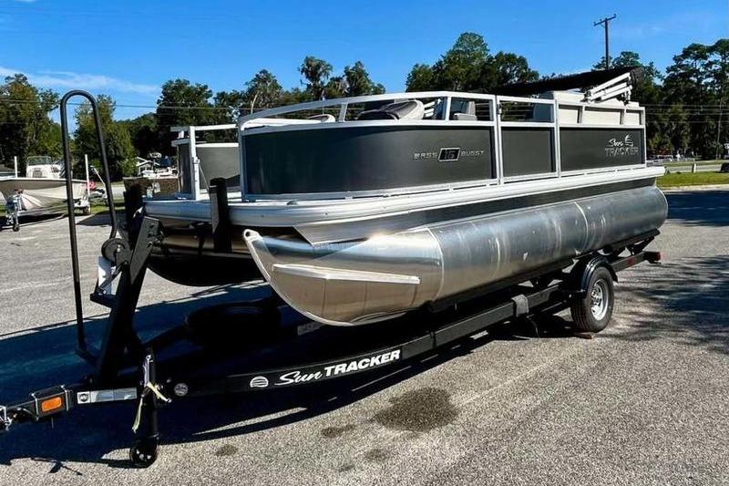2026 Sun Tracker Bass Buggy 16 XL Select pontoon boat on trailer in parking lot.