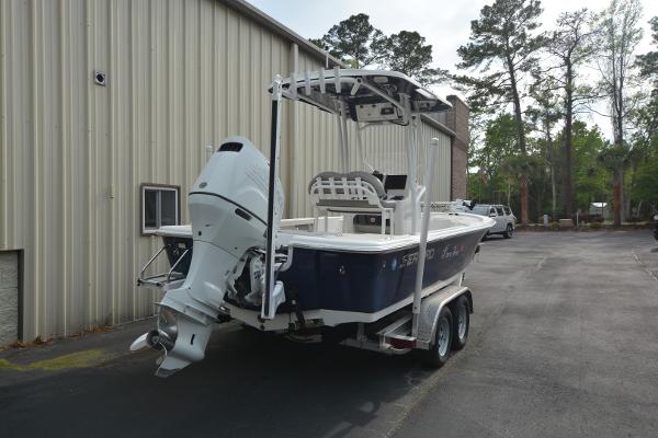 2021 Sea Pro 228 Bay boat on trailer, parked near a building with trees in the background.