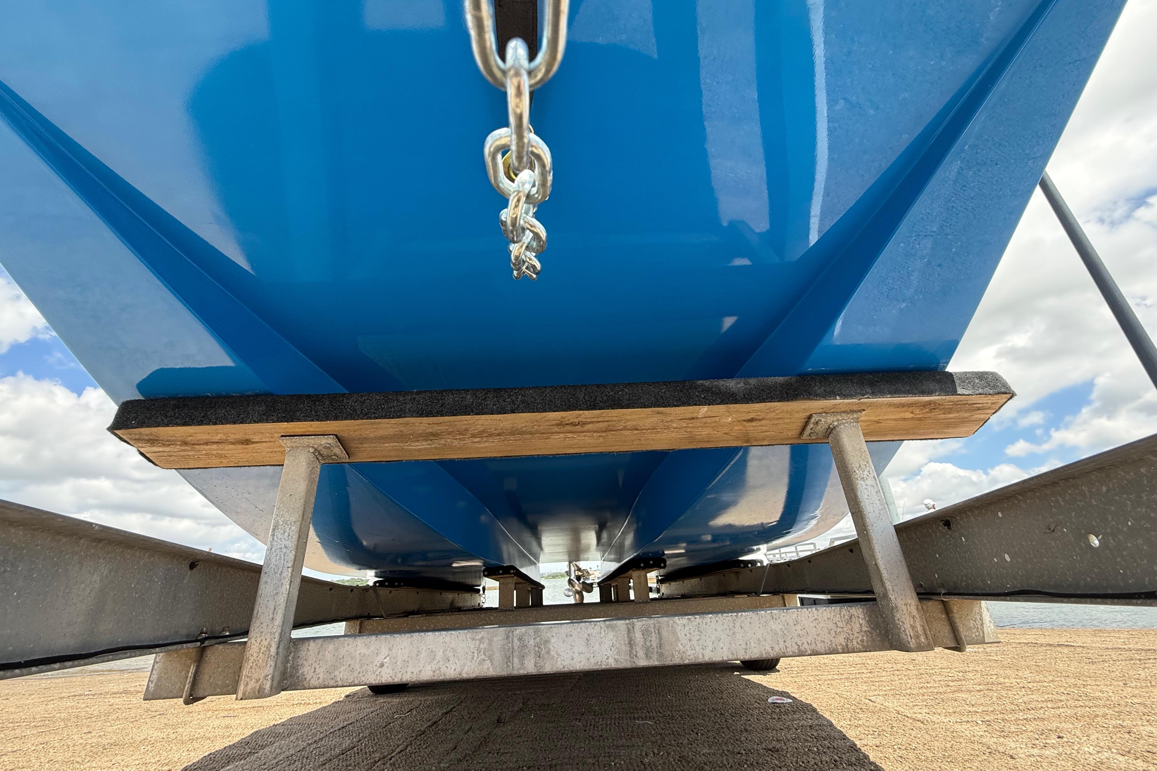 Underneath view of a blue 2007 Flats Cat 19 boat on a trailer.