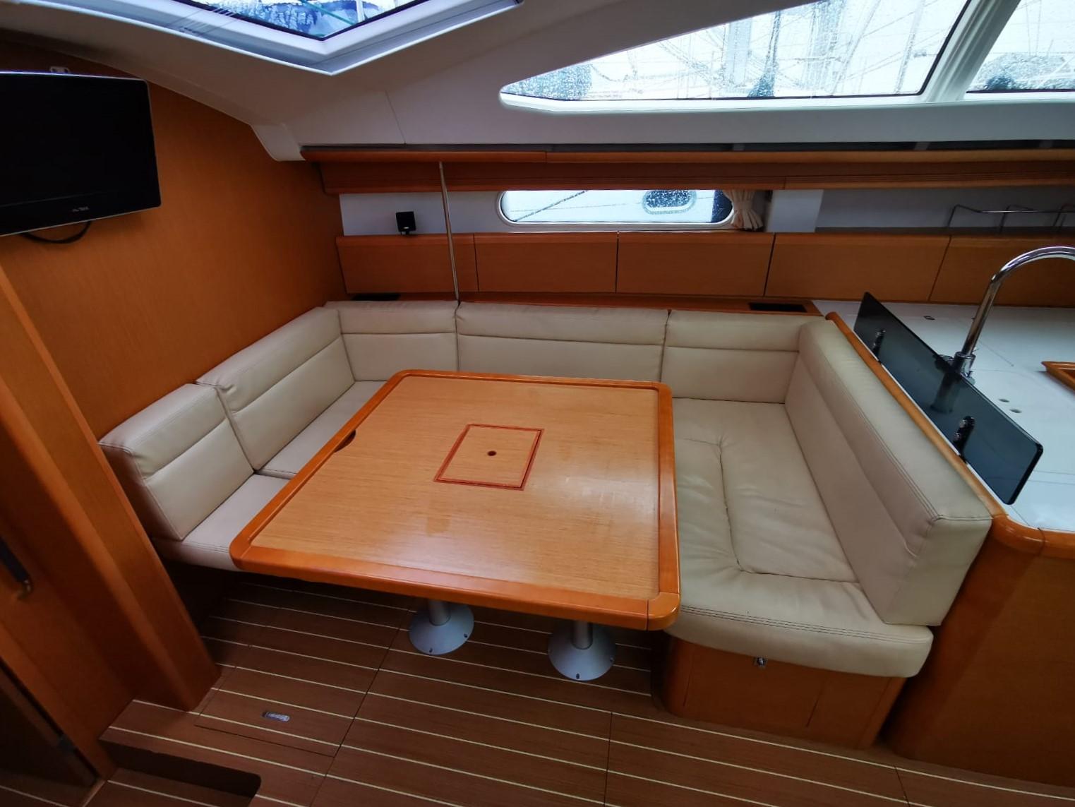 Interior of 2011 Jeanneau Sun Odyssey 45 DS yacht with cozy seating and wooden table.