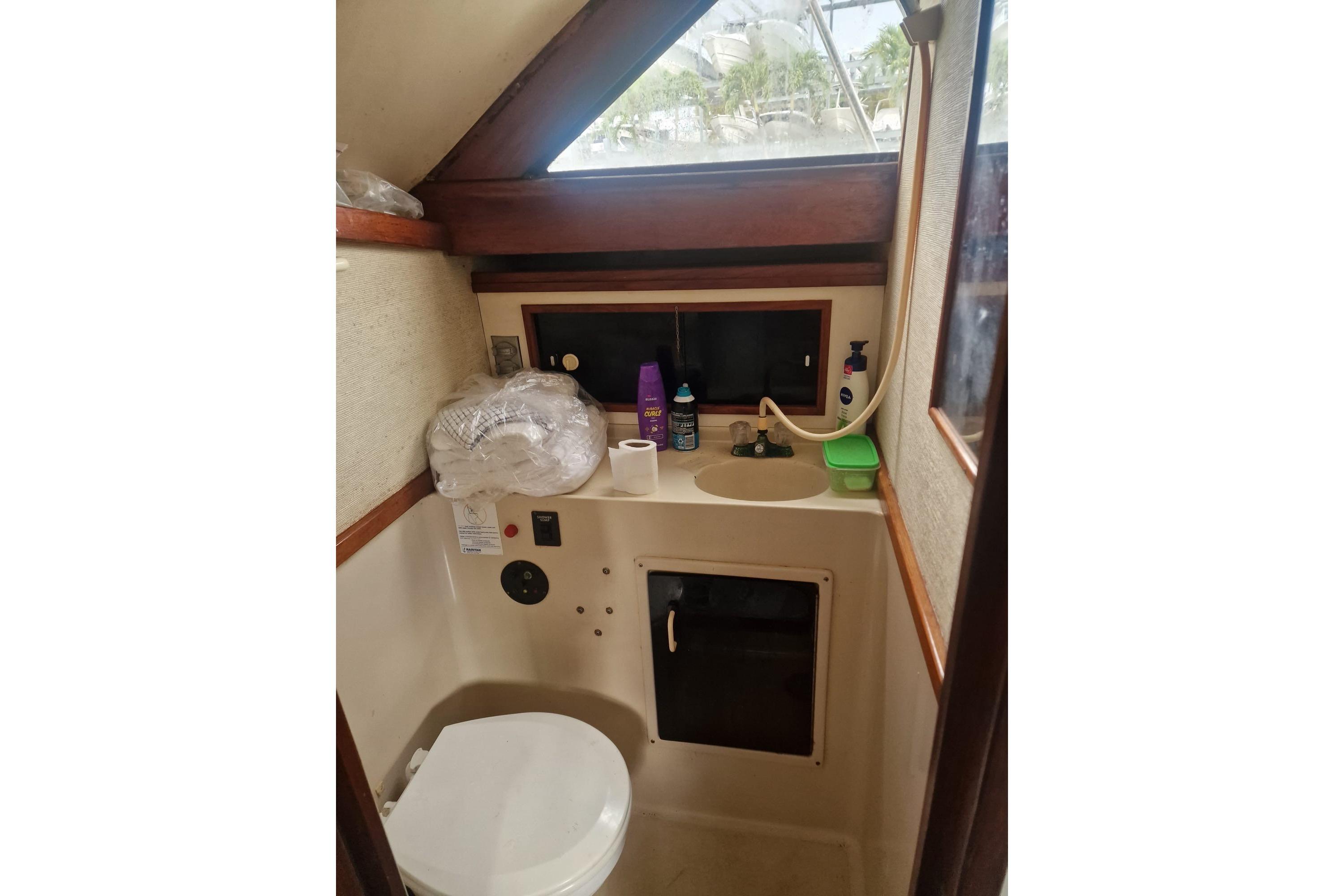 1988 Tiara 3300 Flybridge boat bathroom with sink, toilet, and toiletries.