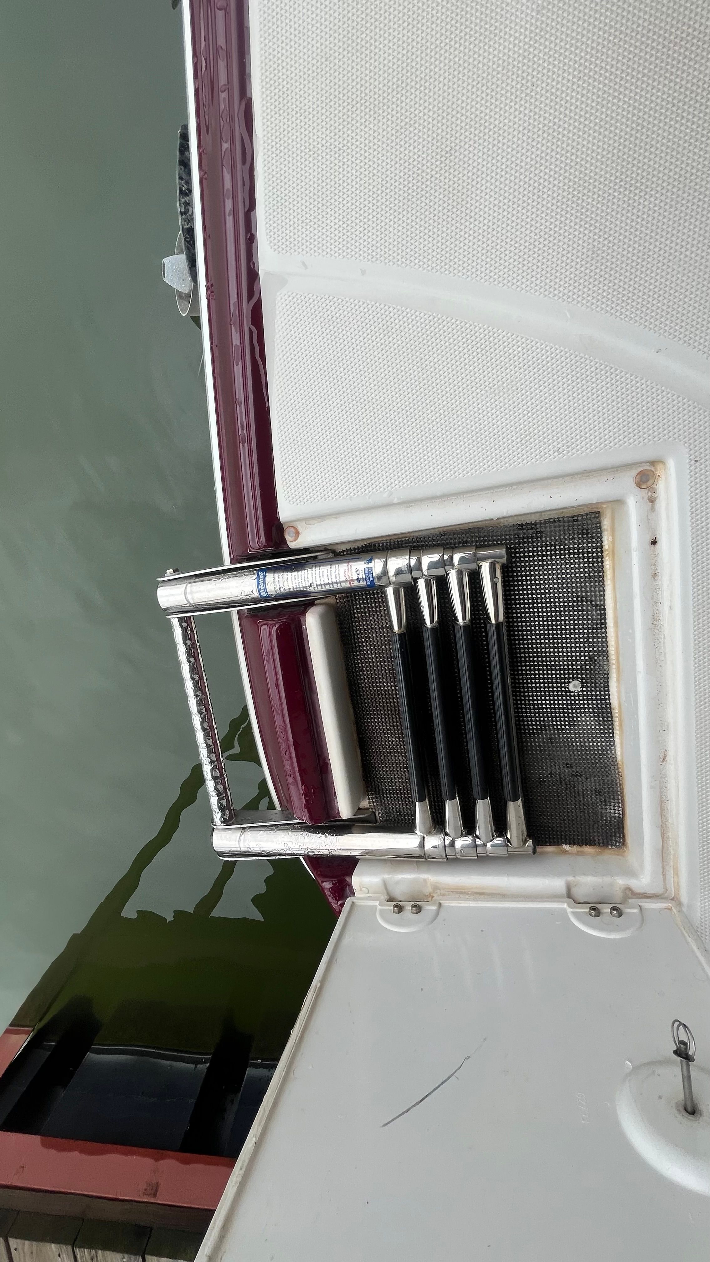 A swim ladder is attached to the stern of a boat, which is on the water.