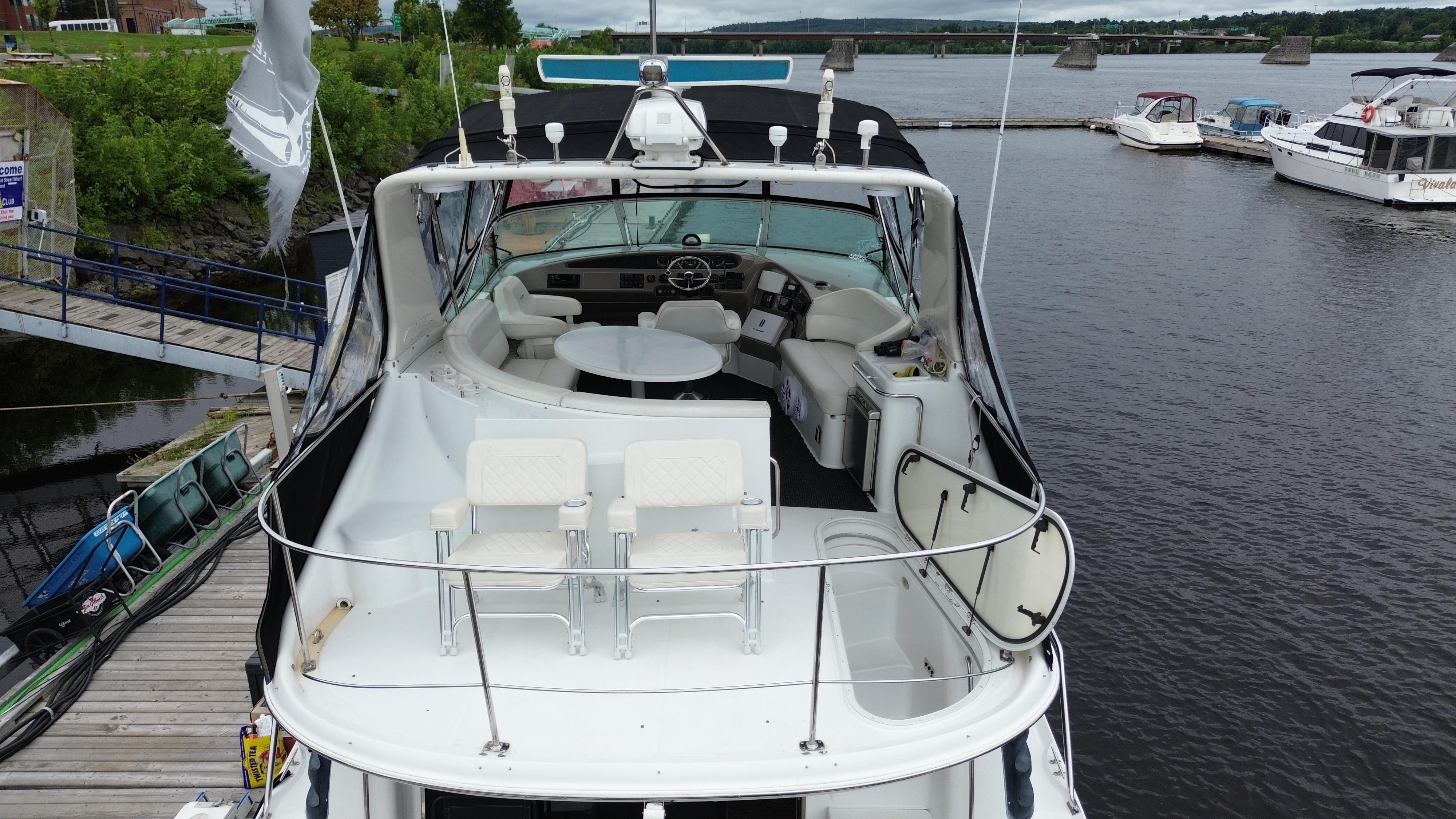 1999 Carver 450 Voyager yacht docked at a marina, featuring spacious deck and seating area.