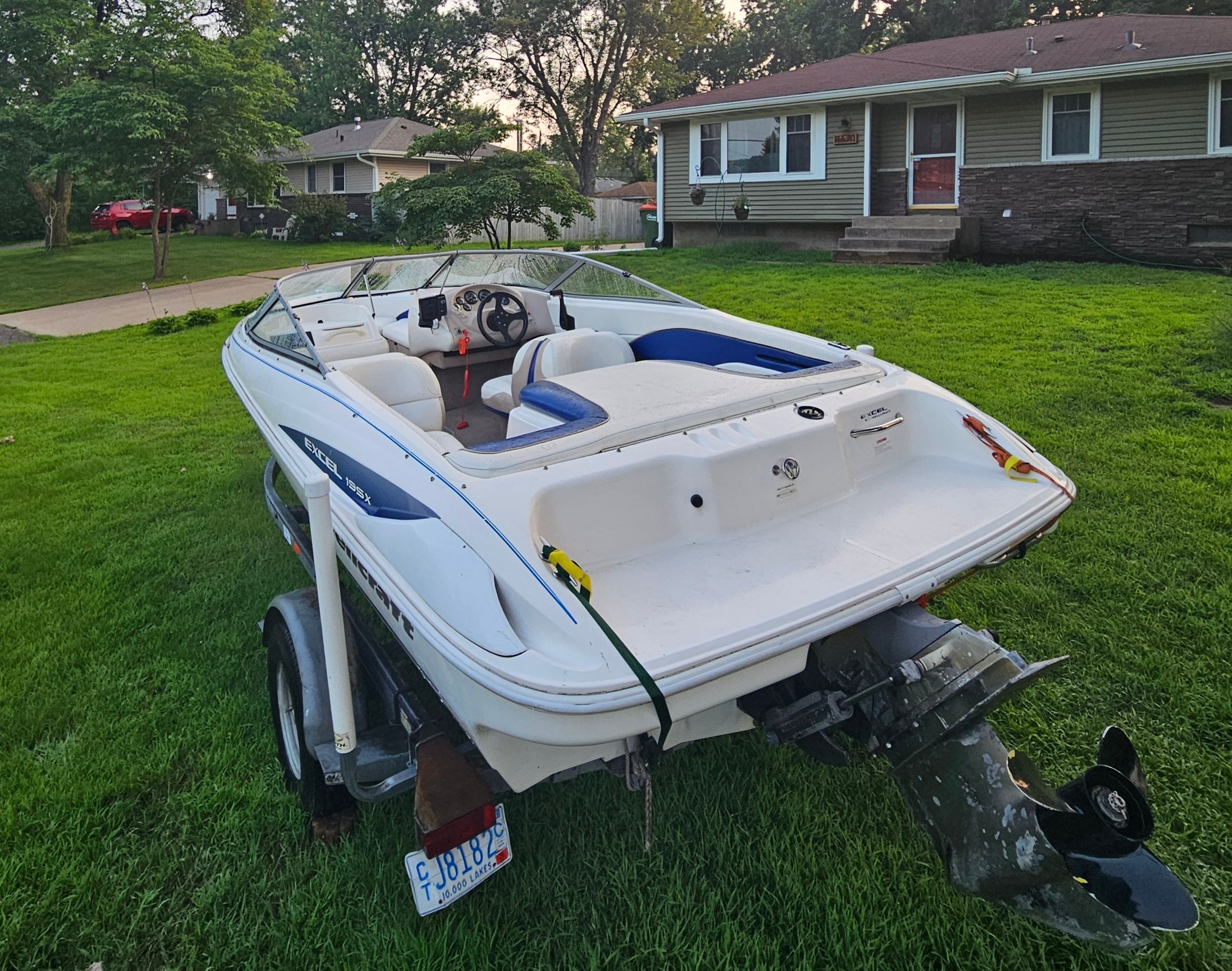 A 1996 Wellcraft Excel boat on a trailer in a grassy yard.