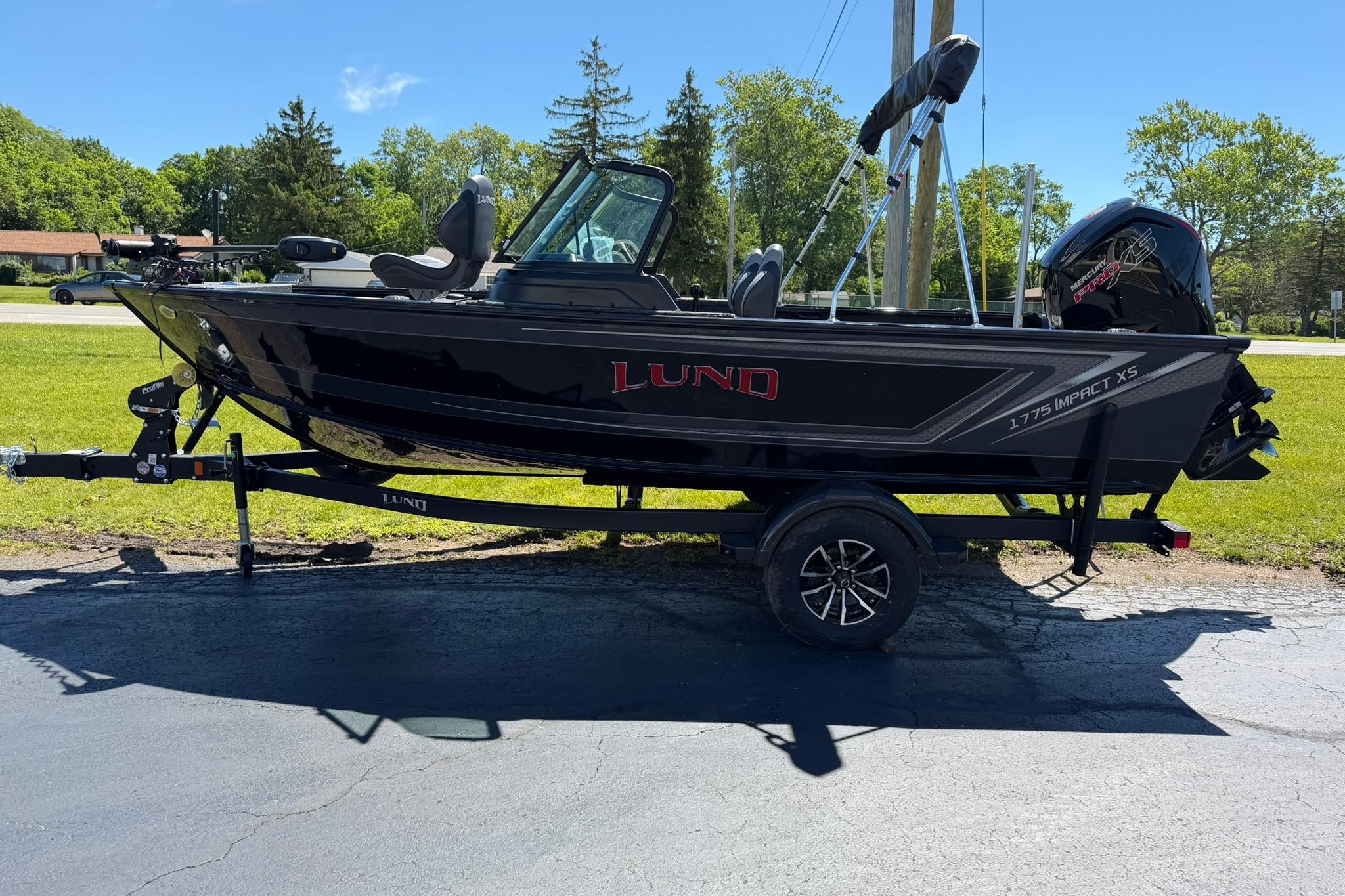 2027 Lund 1775 Impact XS Sport boat on trailer, parked outdoors on sunny day.
