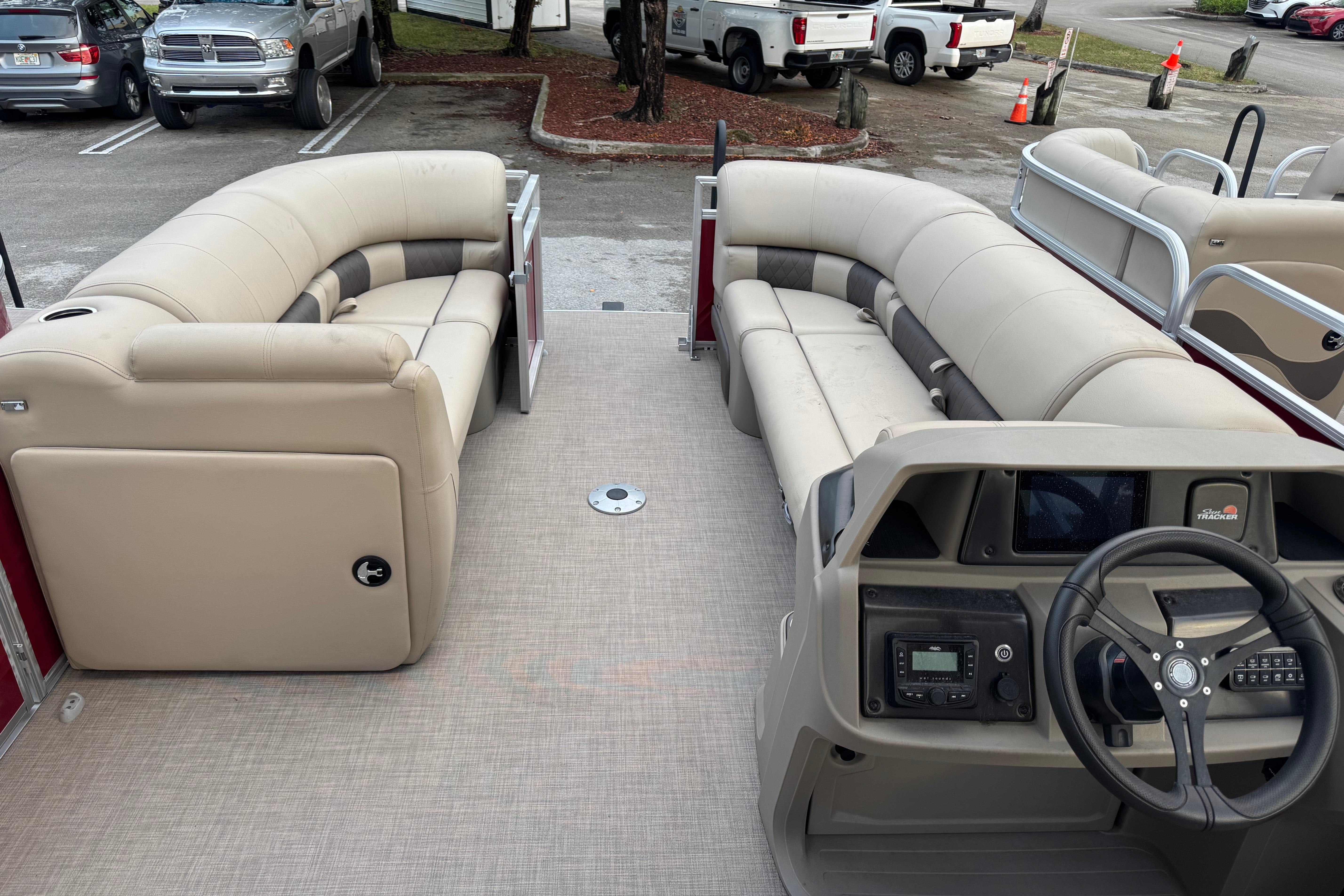 2025 Sun Tracker Party Barge 22 DLX interior with beige seating and steering console.