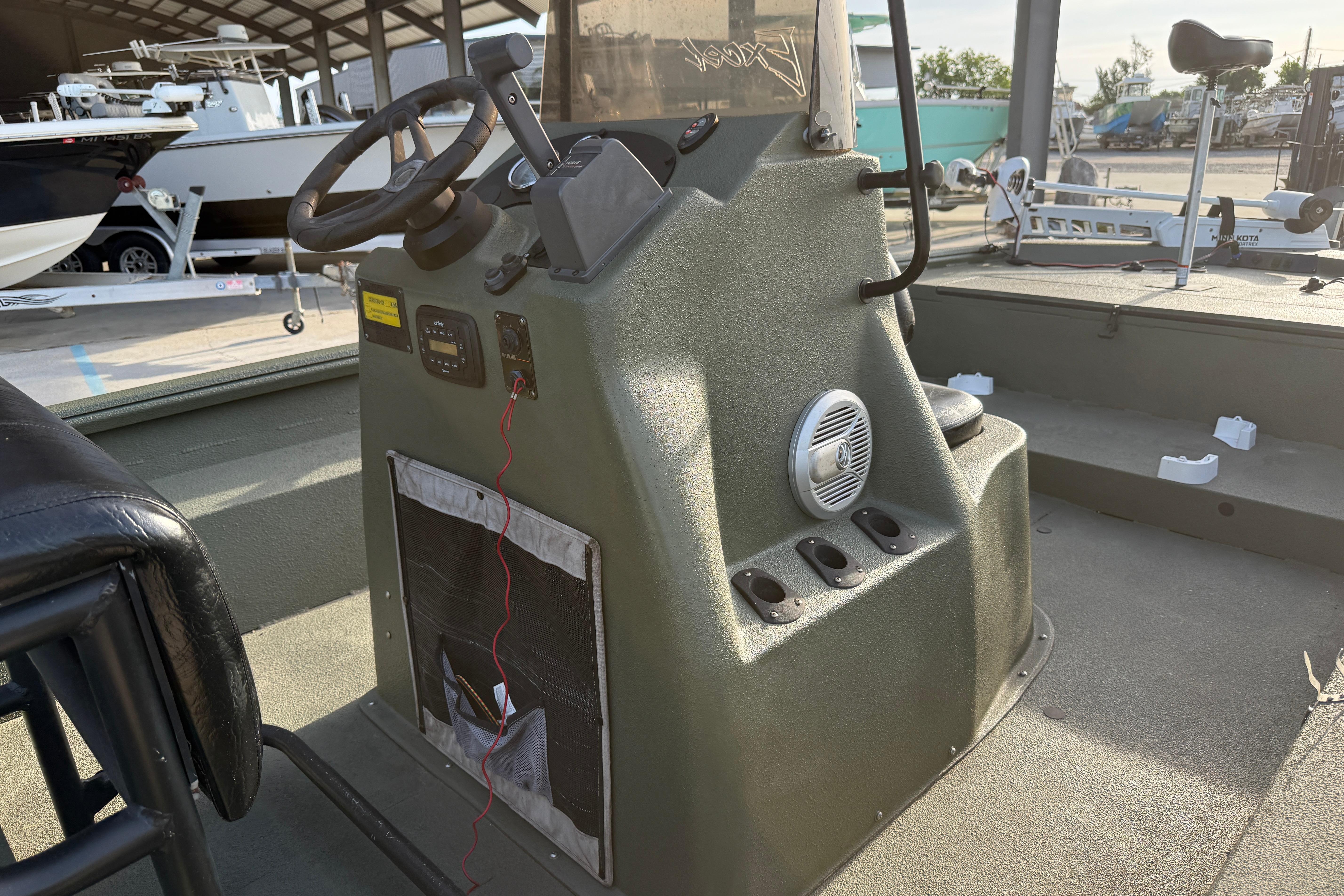 2014 Excel 203 Bay Pro boat console with steering wheel and controls in a marina setting.