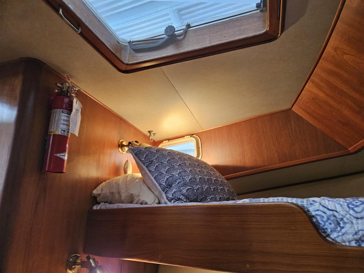 Cozy cabin interior of 1983 Ocean Alexander 43 yacht with wooden bunk and porthole.