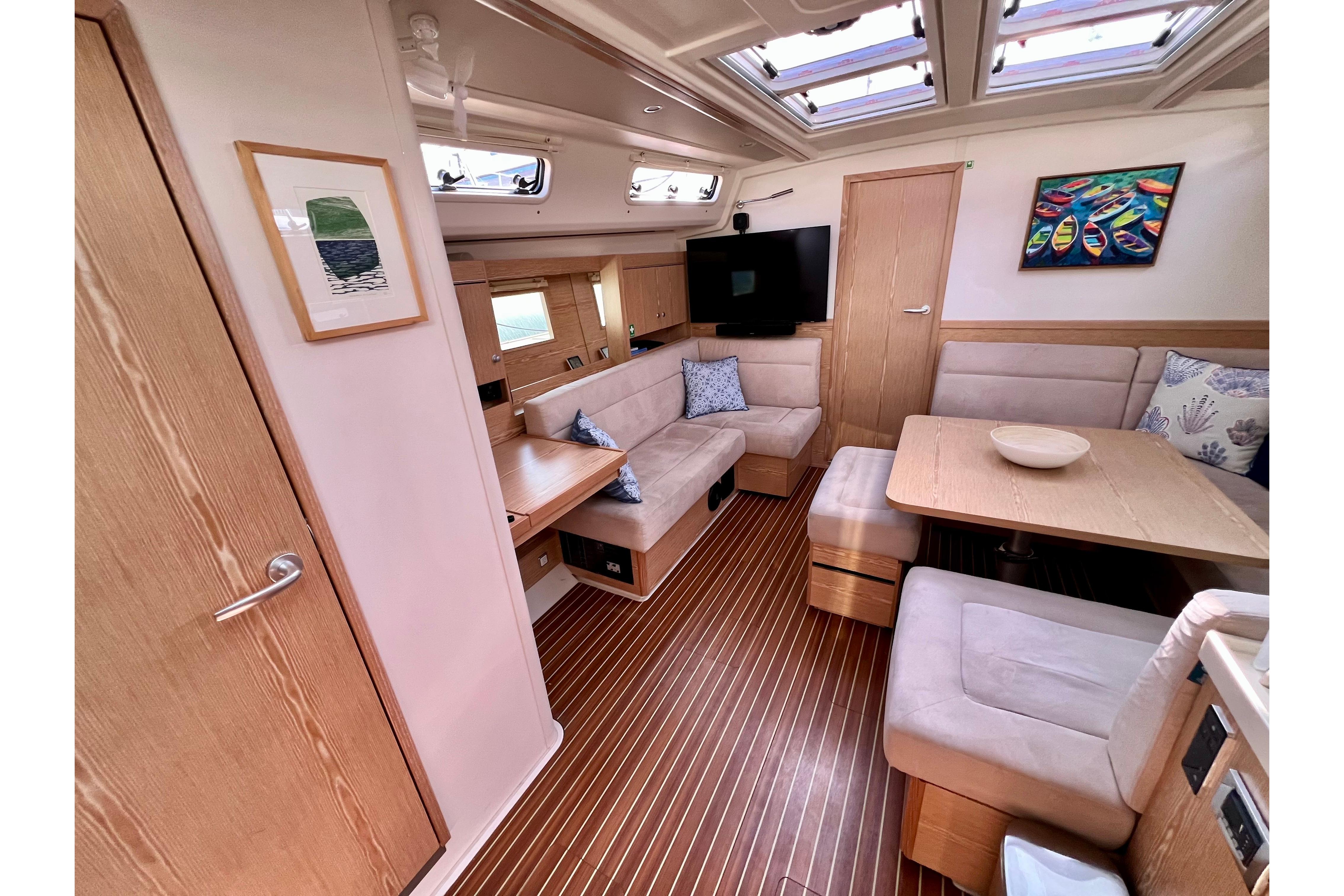 Interior of 2016 Hanse 455 yacht with cozy seating, wooden flooring, and modern decor.