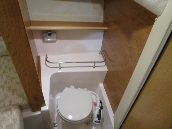 2025 Cutwater C-248 Coupe boat interior bathroom with compact toilet and wooden accents.