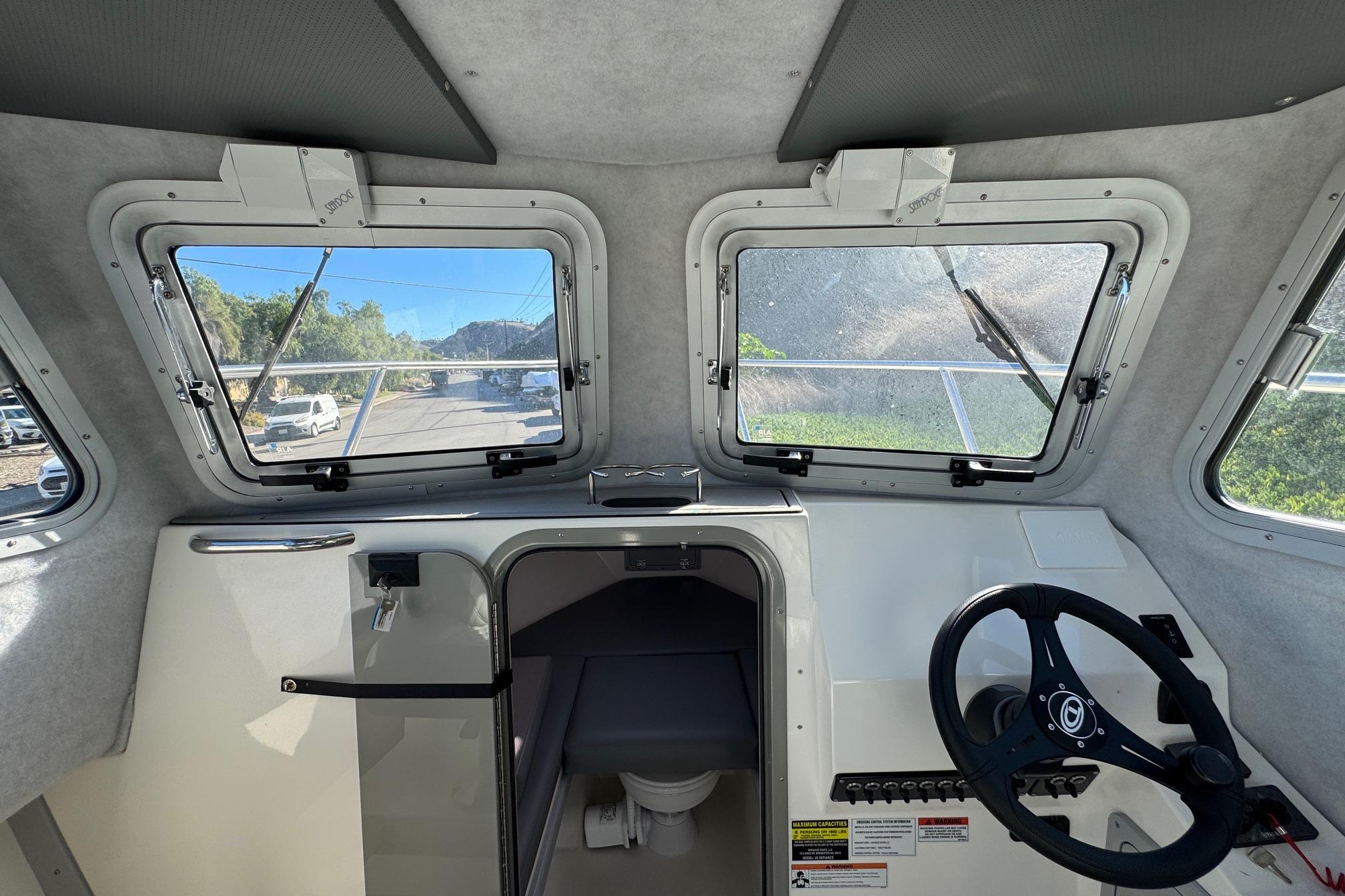 Interior view of 2026 Defiance Admiral 250 EX boat cockpit with steering wheel and windows.