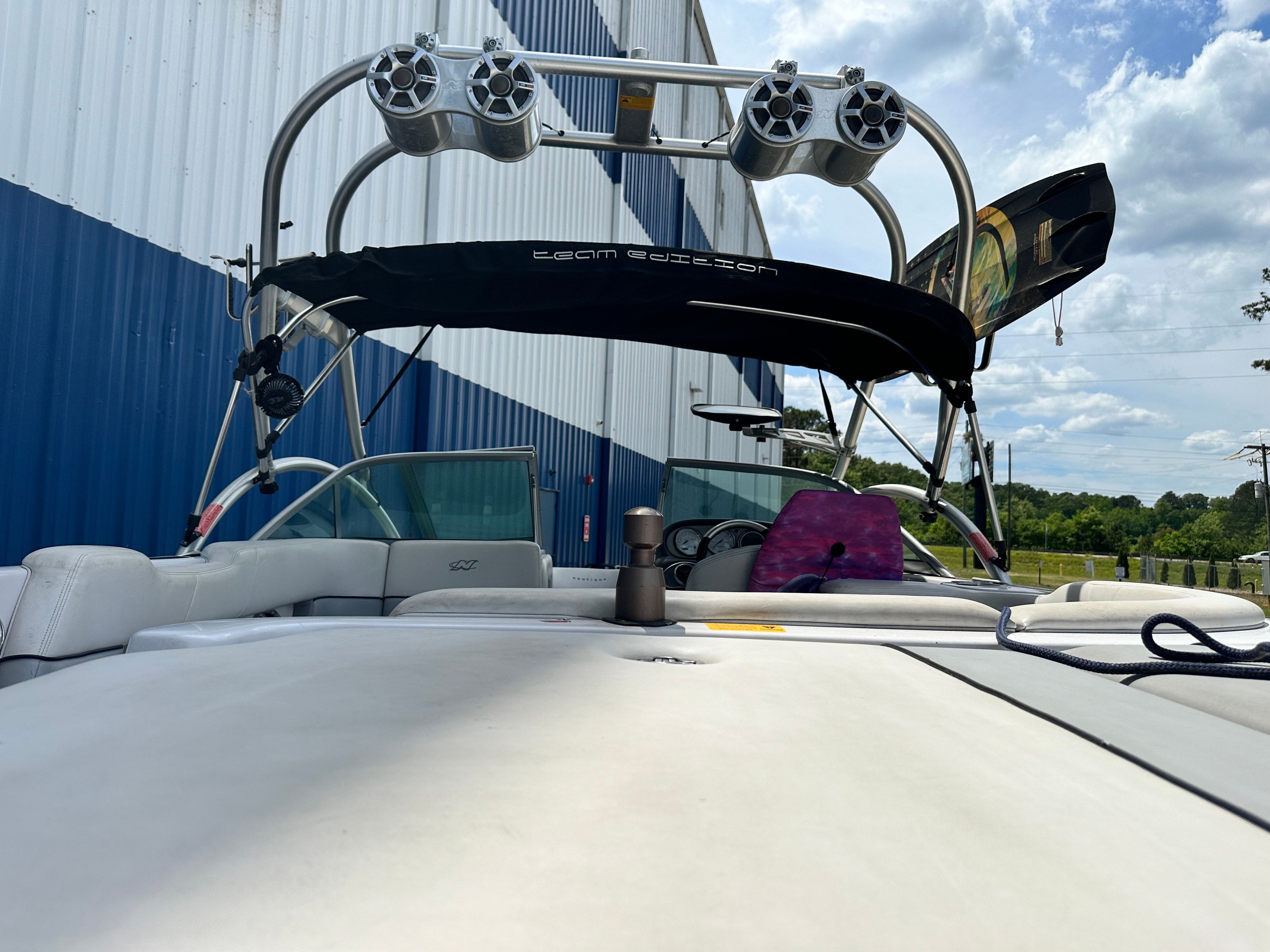 A 2007 Nautique SV 211 boat with tower speakers and a bimini top, parked by a building.