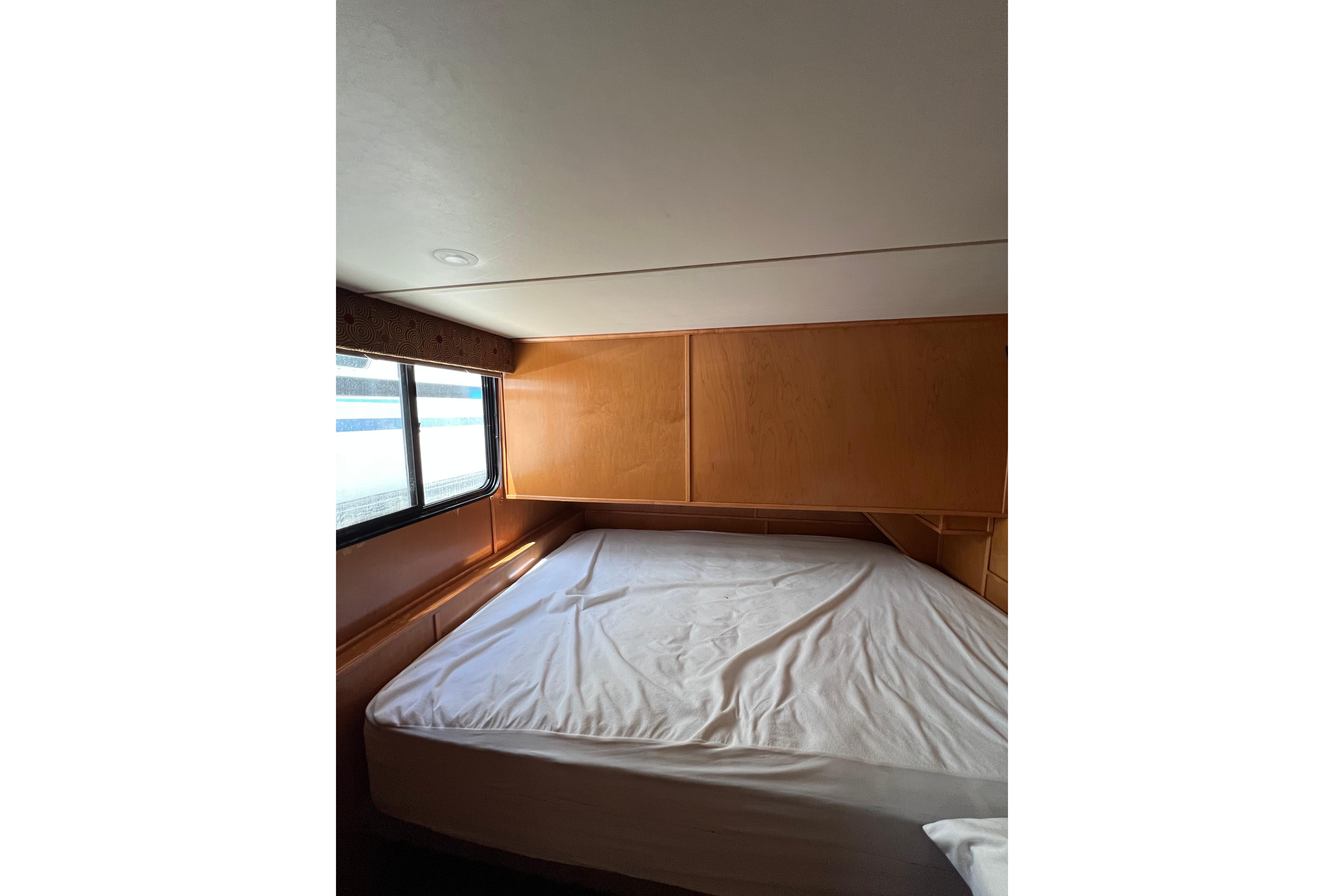 Cozy bedroom interior of 2013 Destination Yacht Lotta Yachta with wooden paneling and window.