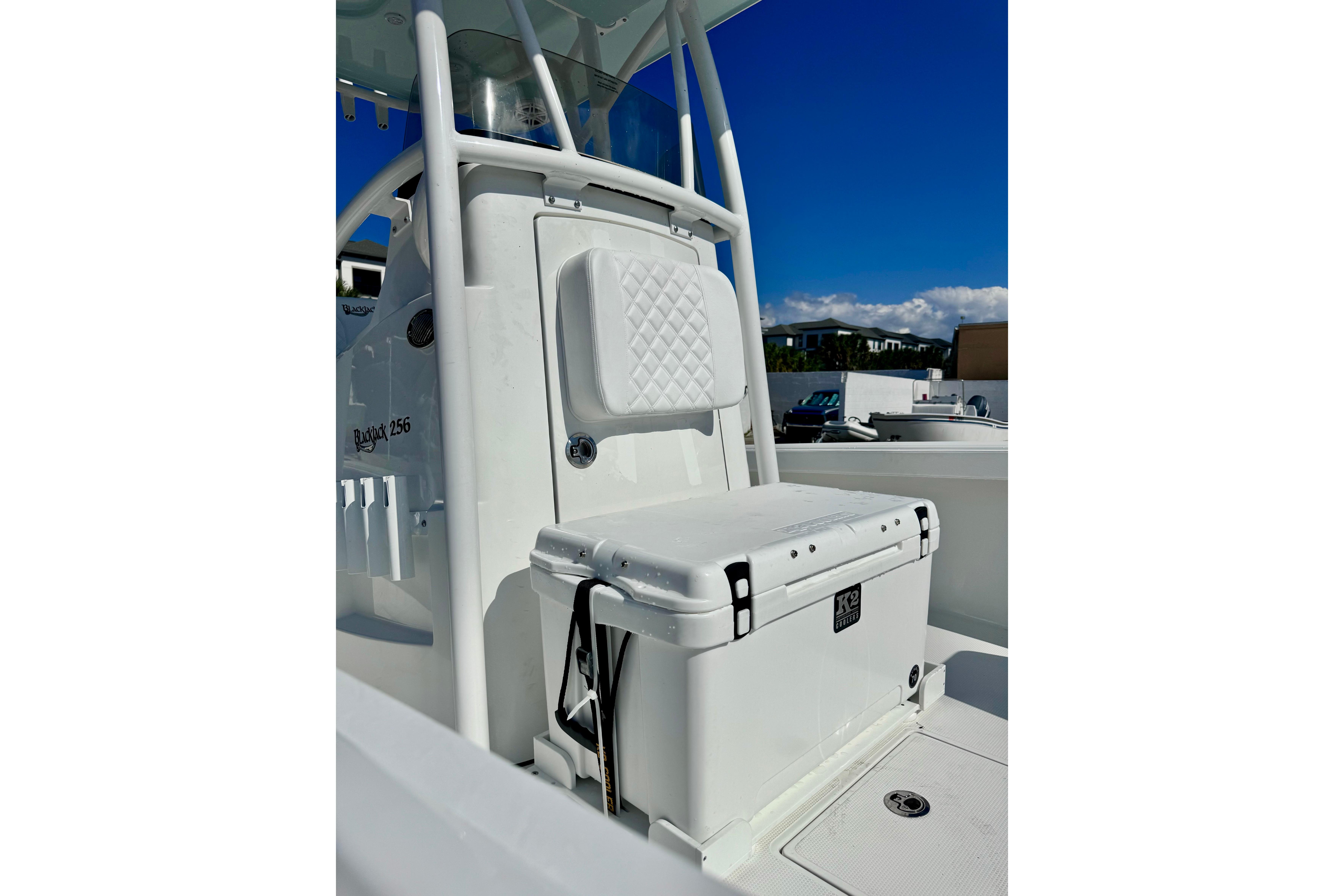 2026 BlackJack 256 Coastal boat interior with seating and storage, under clear blue sky.