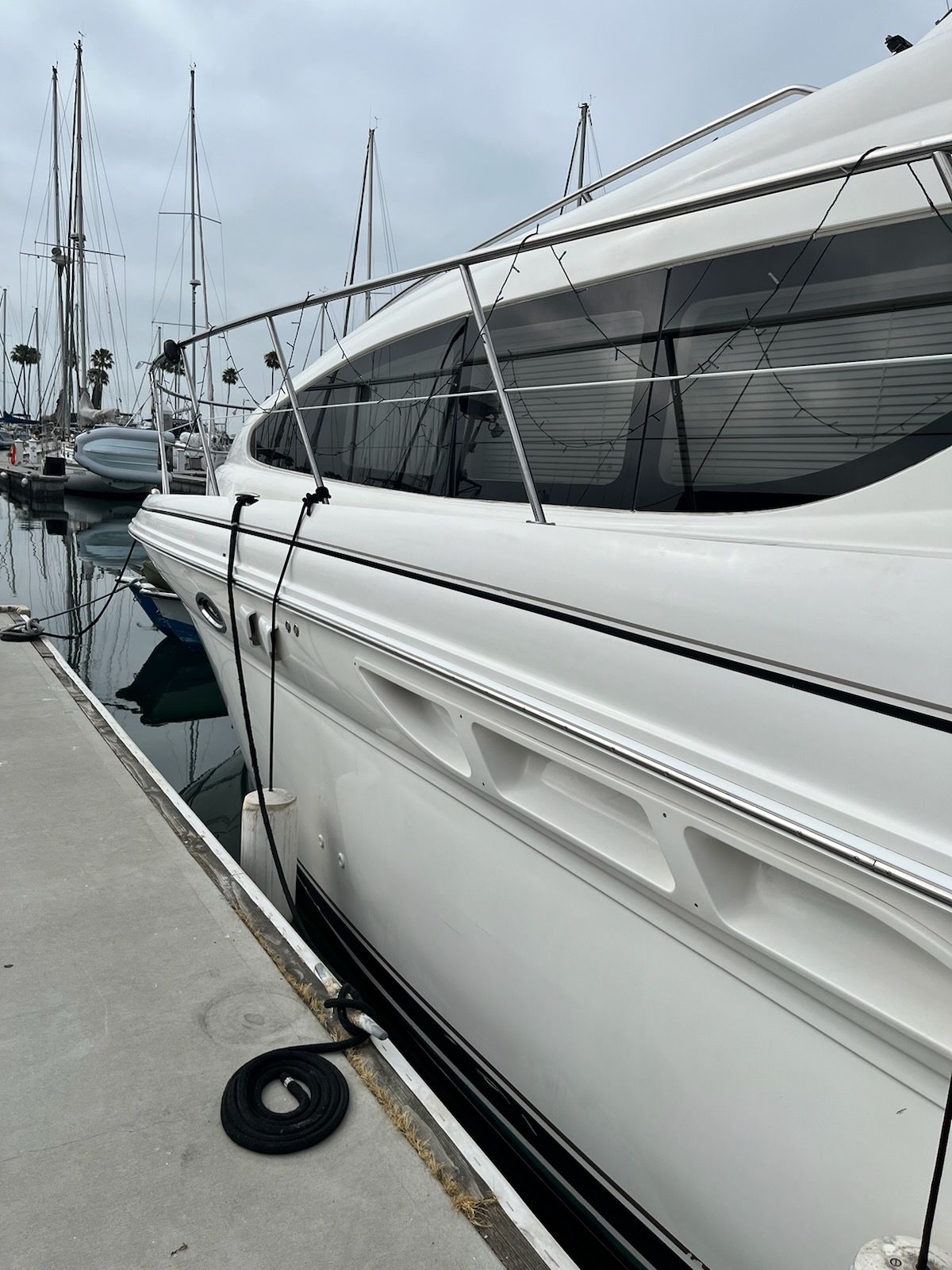 A 2004 Sea Ray Sedan Bridge docked at a marina. Several sailboats are visible in the background.
