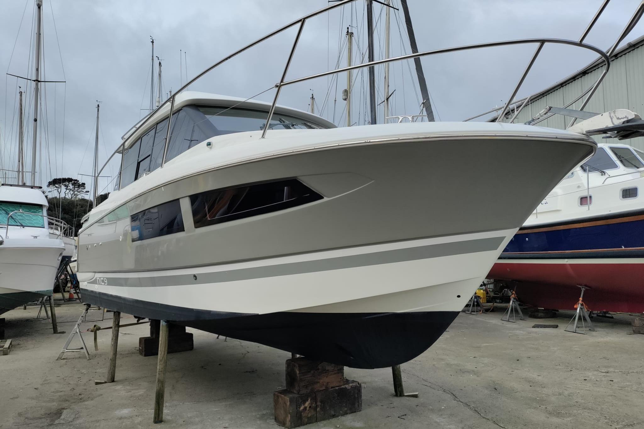 2013 Jeanneau NC 9 boat on dry dock, surrounded by other vessels.