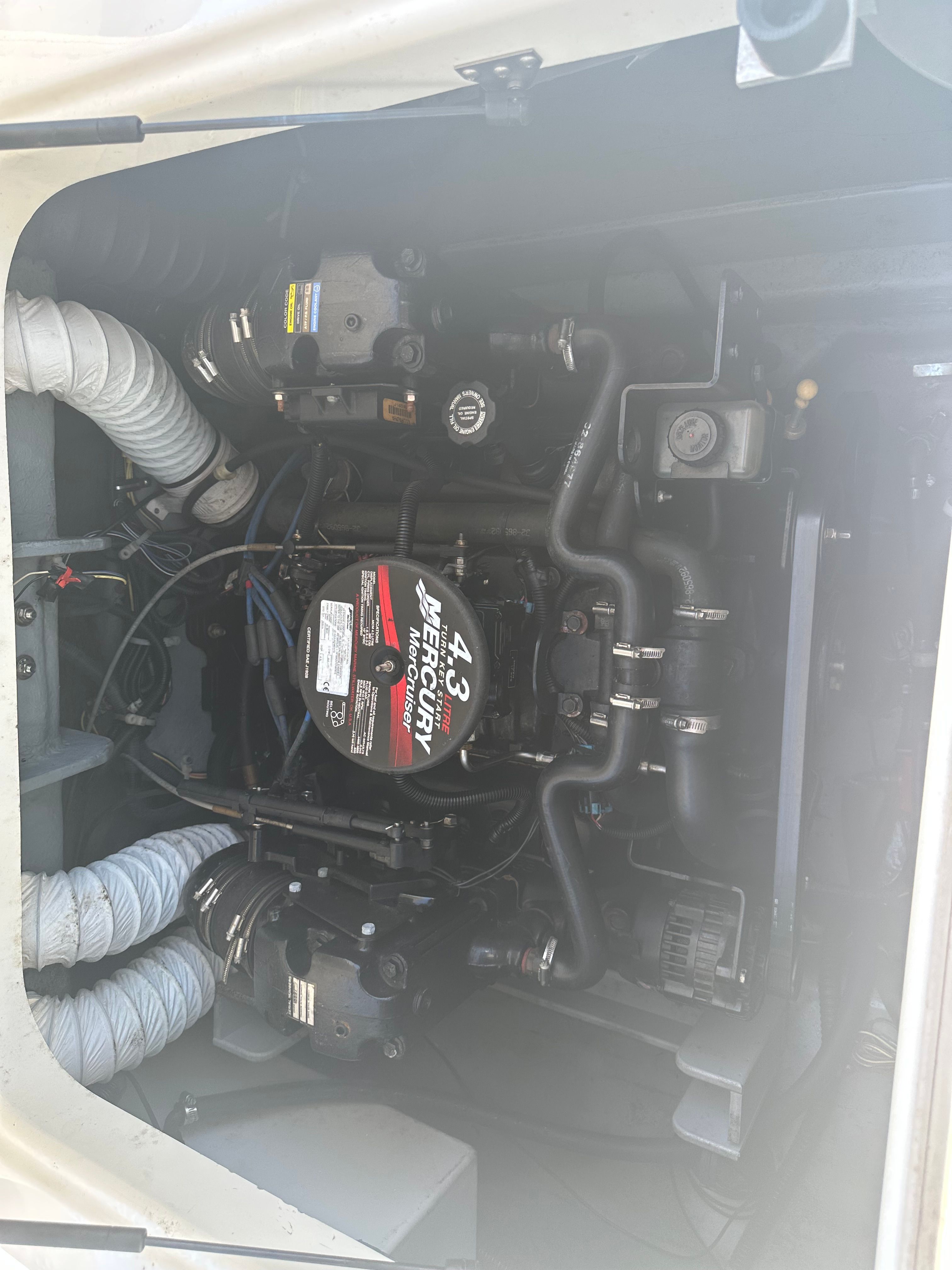A Mercury engine in a Bayliner boat, surrounded by hoses and cables.