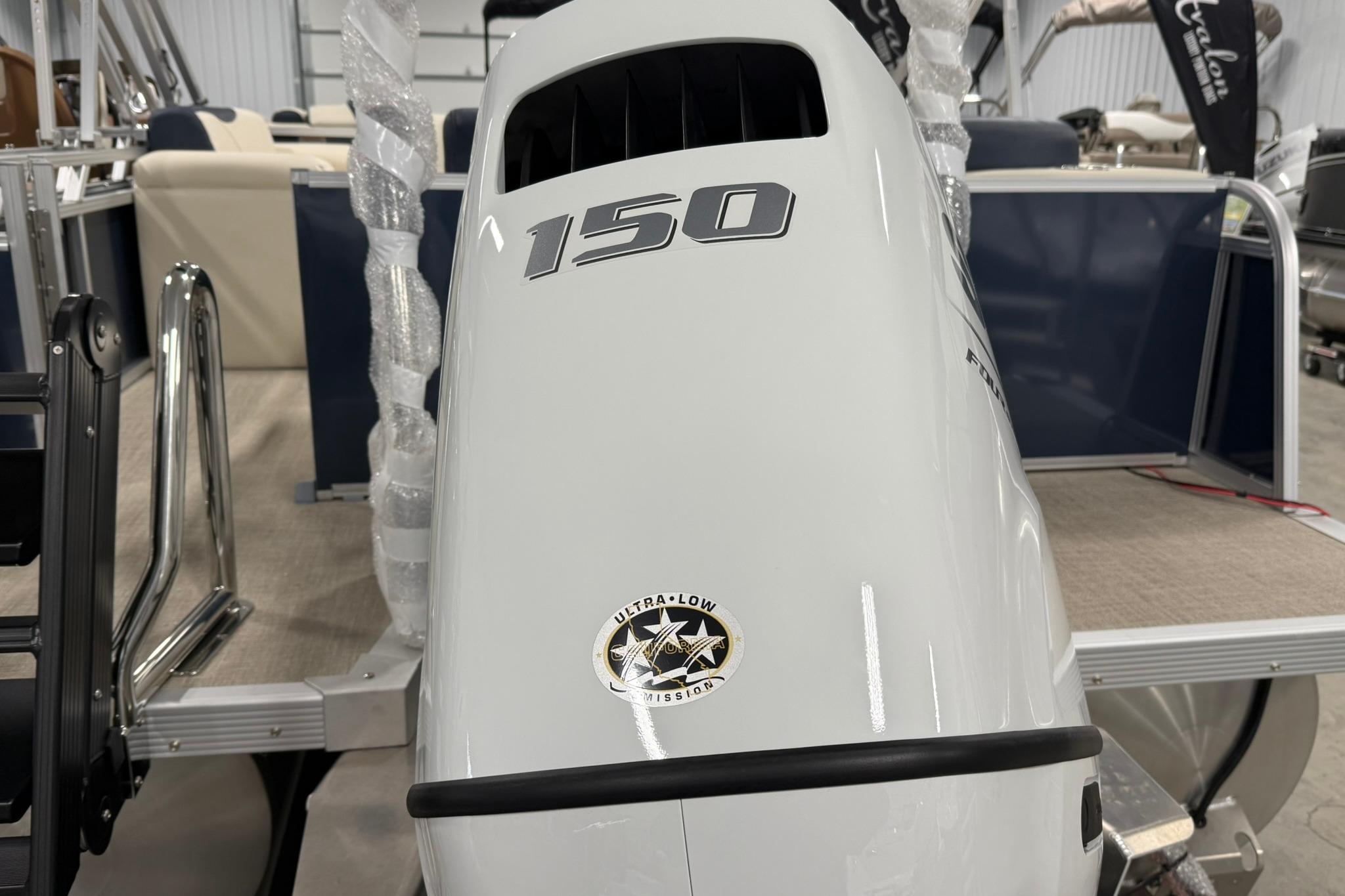 2026 Avalon LSZ Elite 21' boat with 150 horsepower engine, displayed indoors.