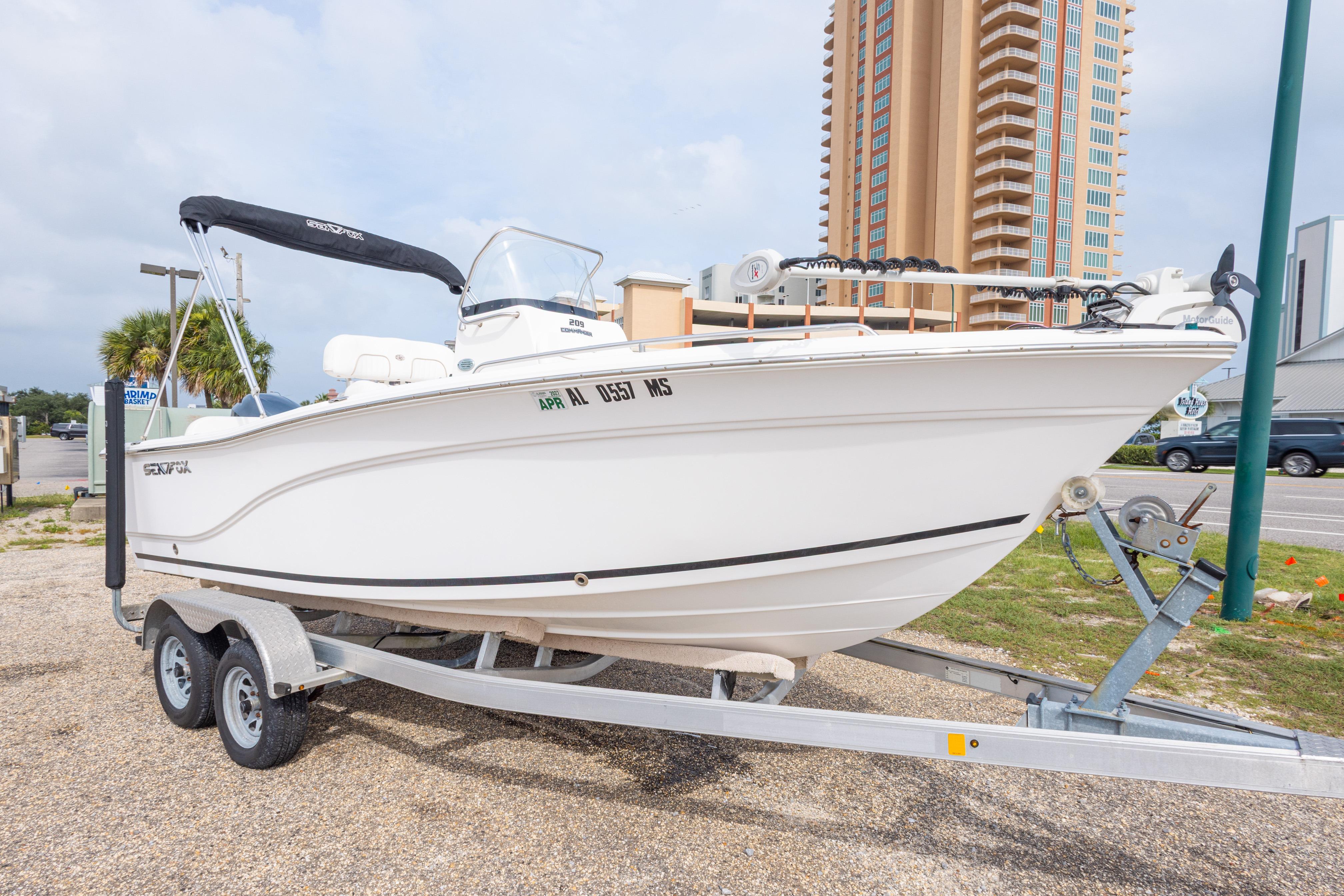 2014 Sea Fox 209 Commander boat on trailer, parked near tall building.