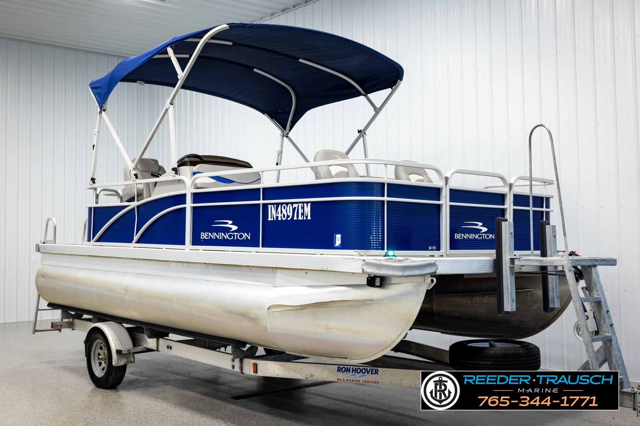 2021 Bennington 20 SV pontoon boat with blue canopy on trailer in showroom.