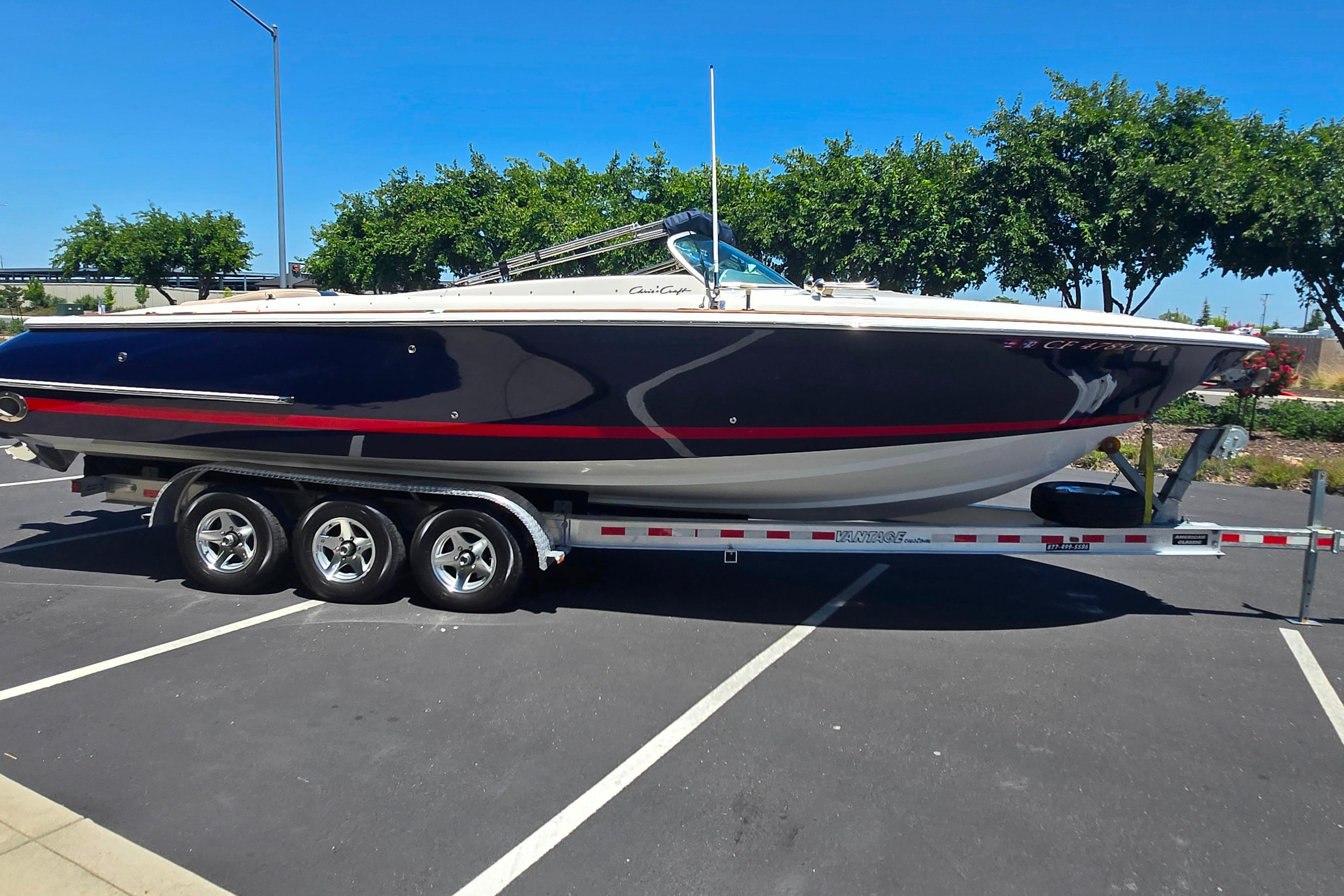 2002 Chris-Craft Launch 28 GT I/O boat on trailer in parking lot.