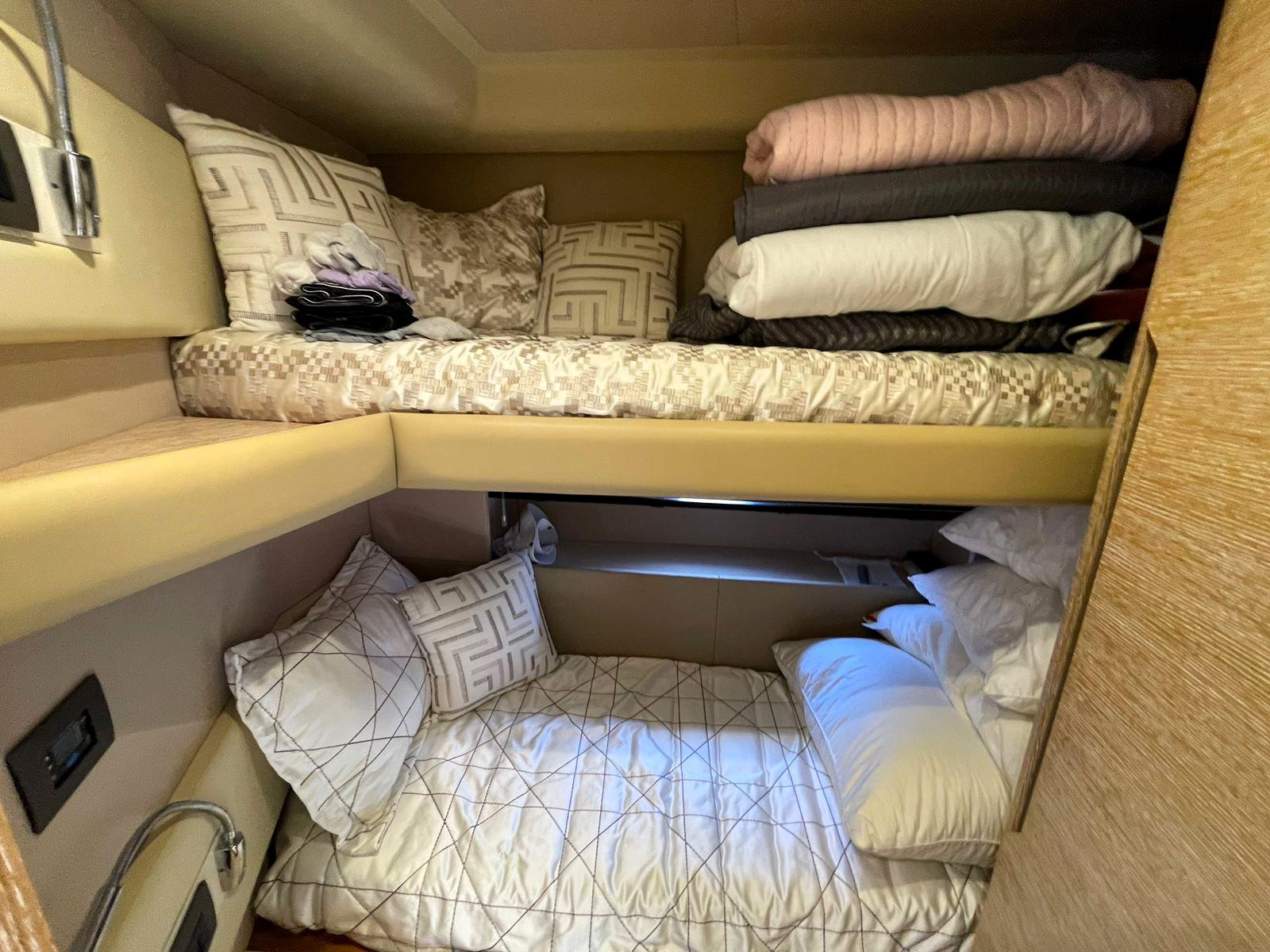 Cozy bunk beds in a 2016 Azimut 50 yacht cabin with plush pillows and blankets.