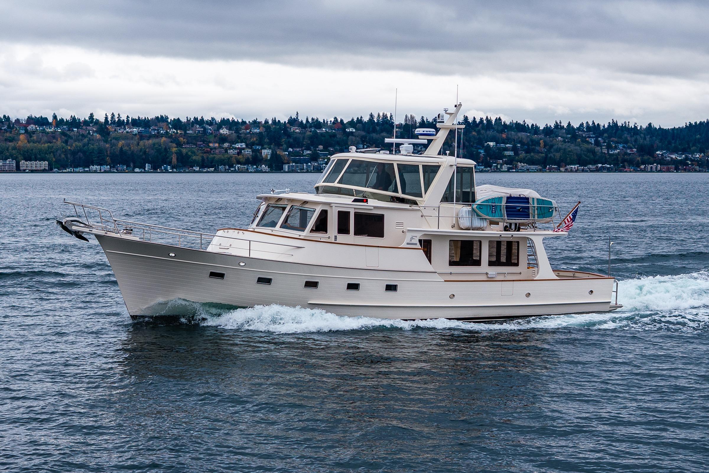 2026 Fleming 55 Pilothouse yacht cruising on a scenic lake under cloudy skies.