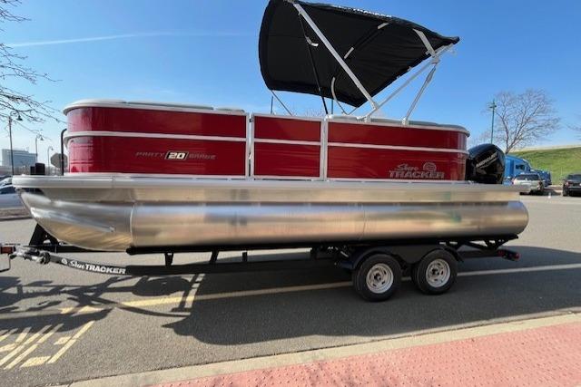 2026 Sun Tracker Party Barge 20 DLX pontoon boat on trailer, parked outdoors.