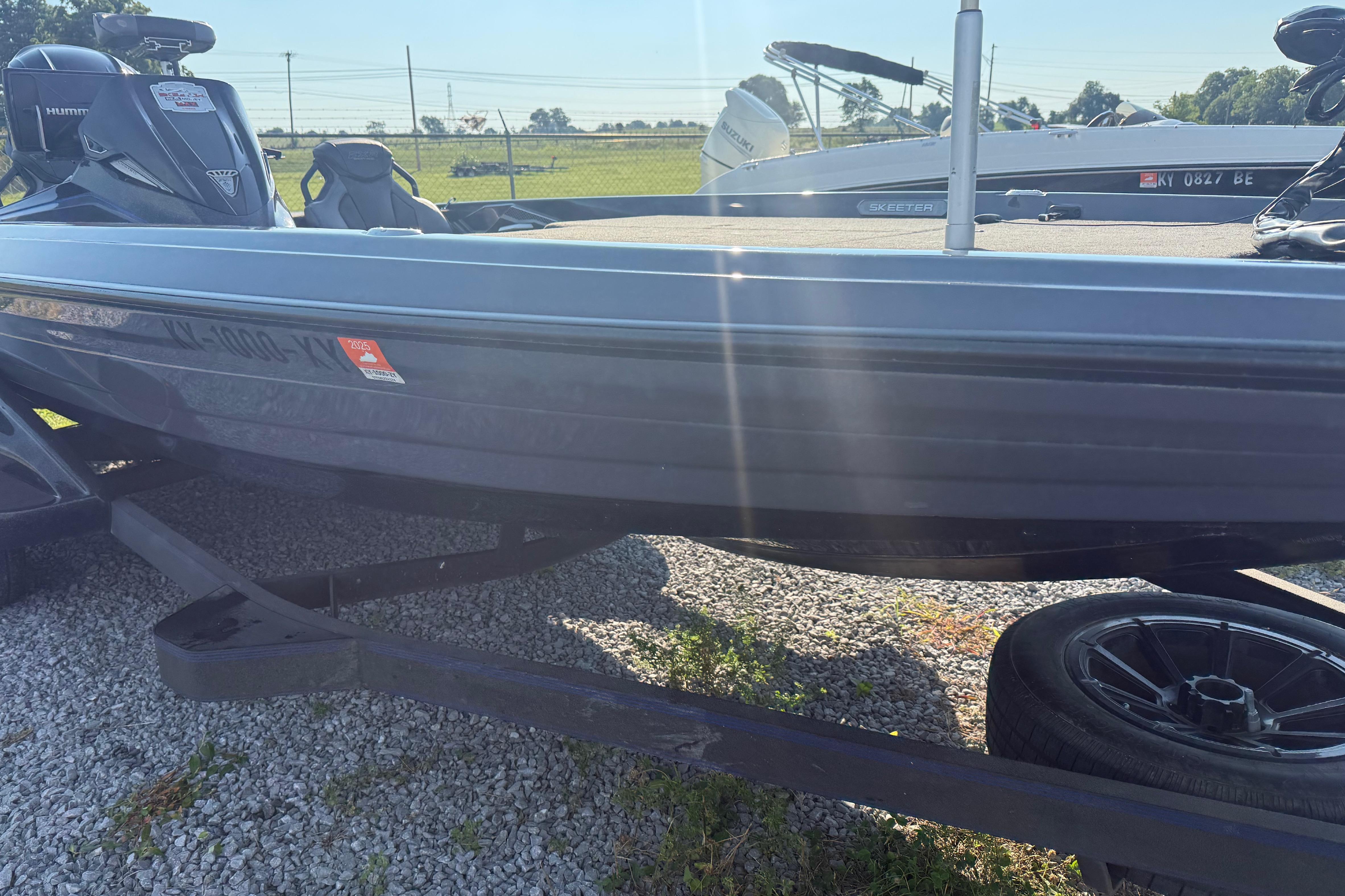 2024 Skeeter FXR21 boat on trailer, parked on gravel, sunny day.