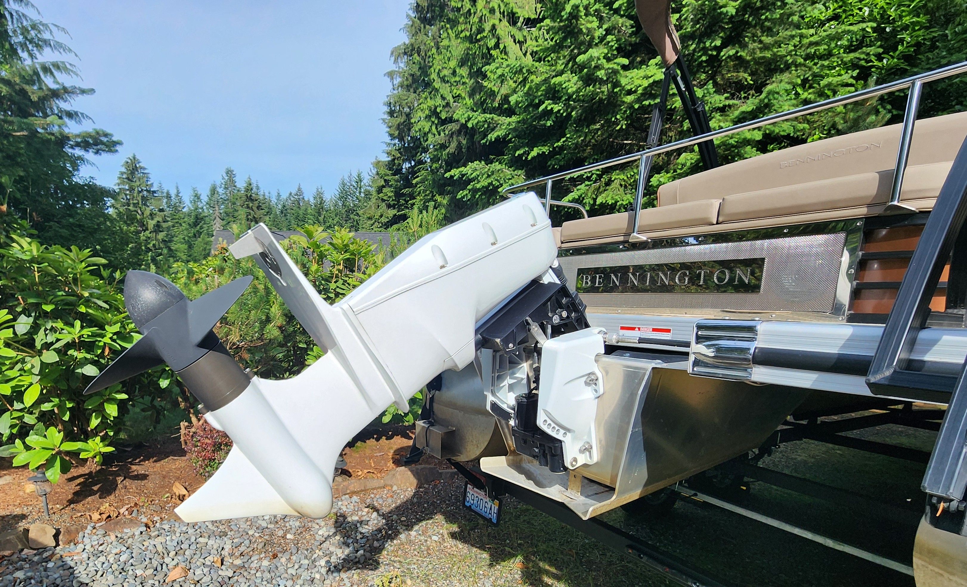 A 2023 Bennington 22 LSB with an outboard motor, surrounded by lush greenery.