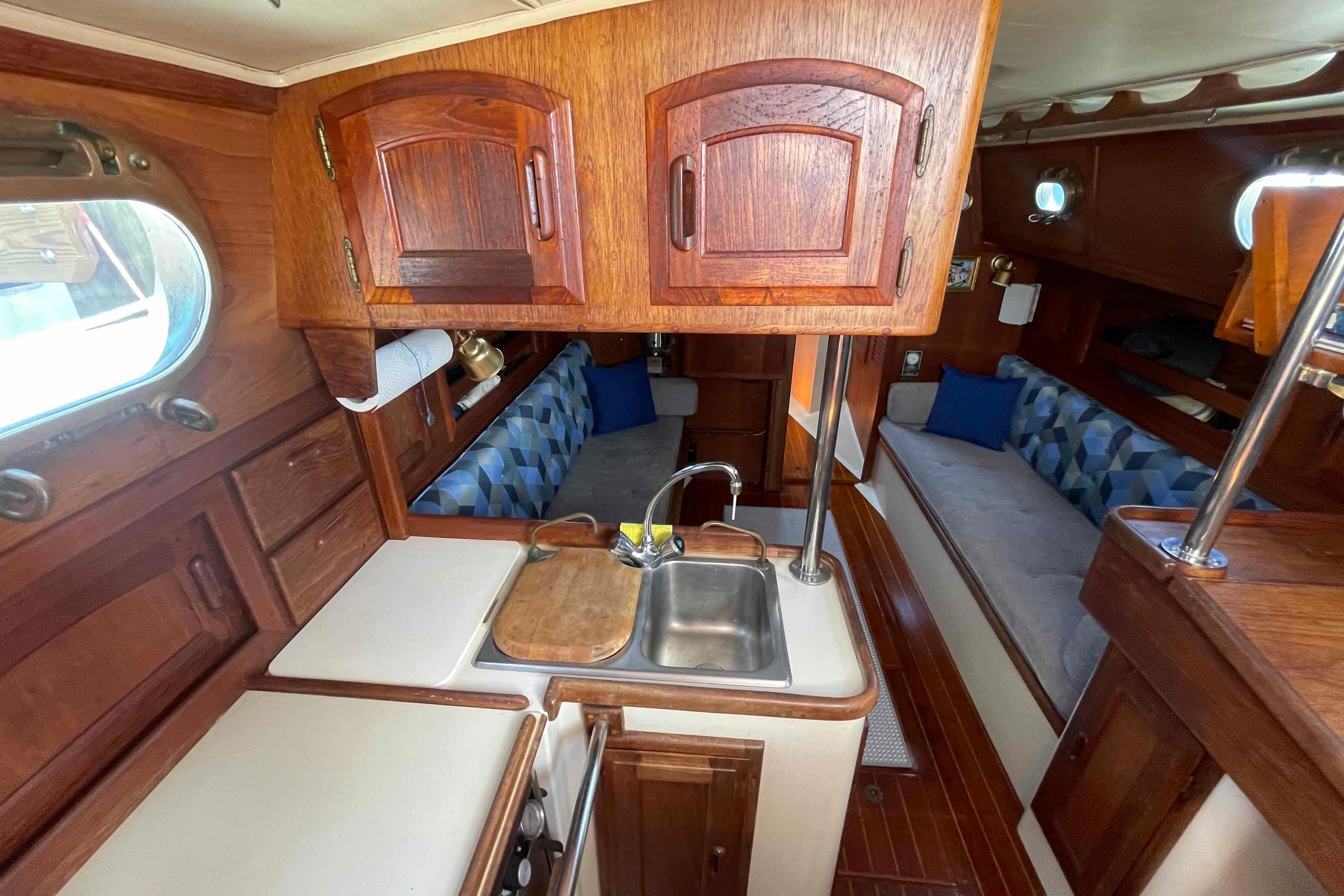 Interior of 1987 Pacific Seacraft 34 sailboat with wooden cabinetry and cozy seating area.
