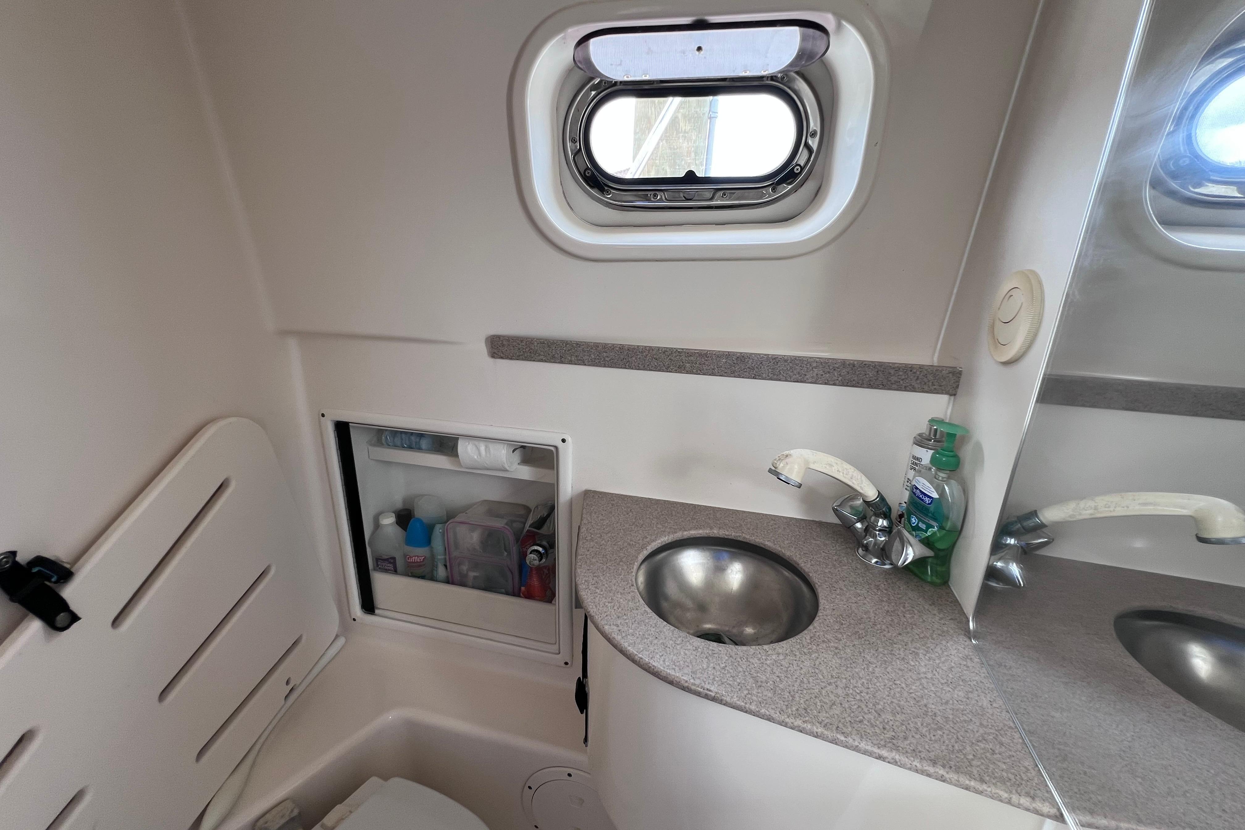 2005 Pursuit 3070 Offshore boat bathroom with sink, mirror, and storage cabinet.