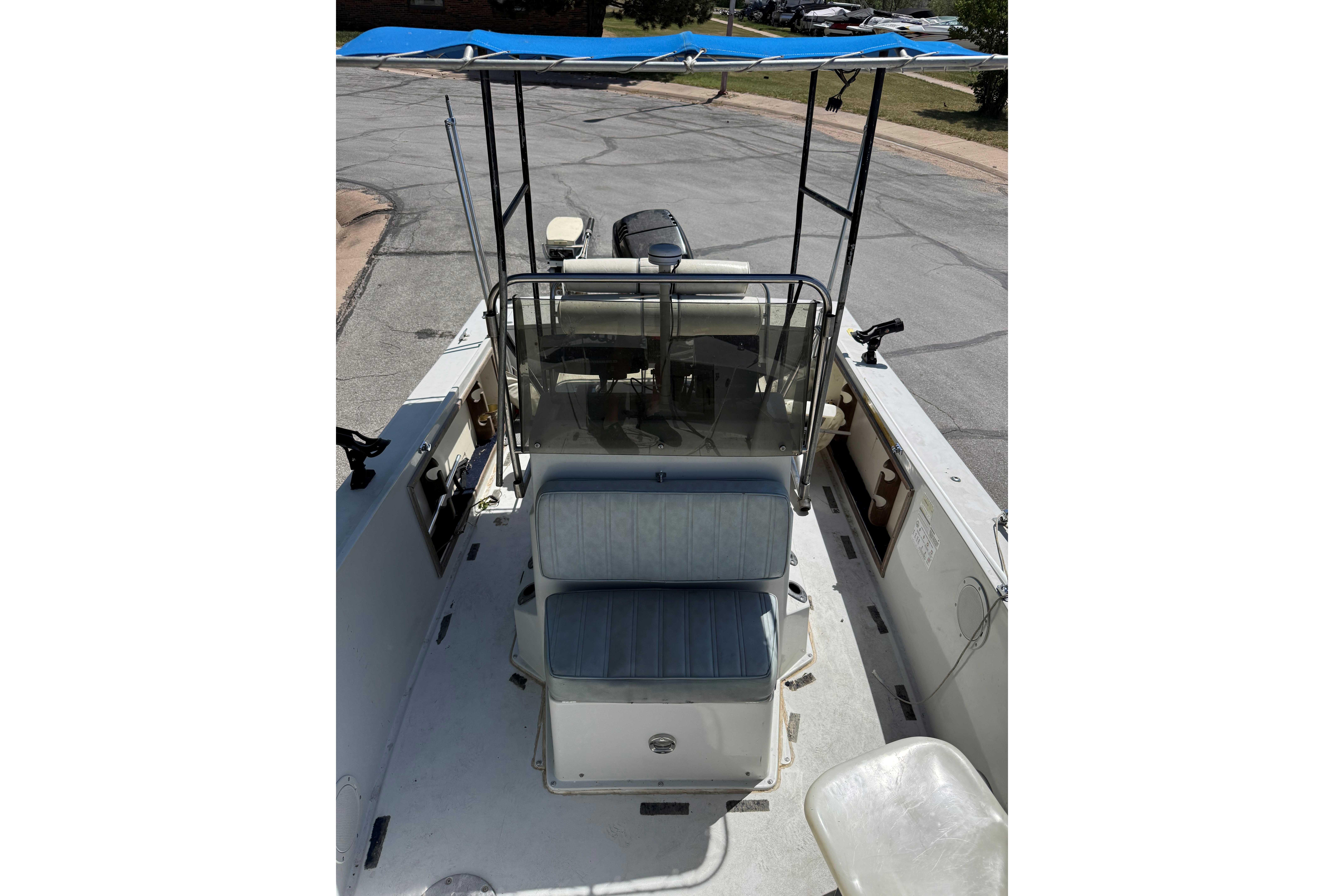1985 Wellcraft 180 Fisherman boat with blue canopy and seating, parked on pavement.