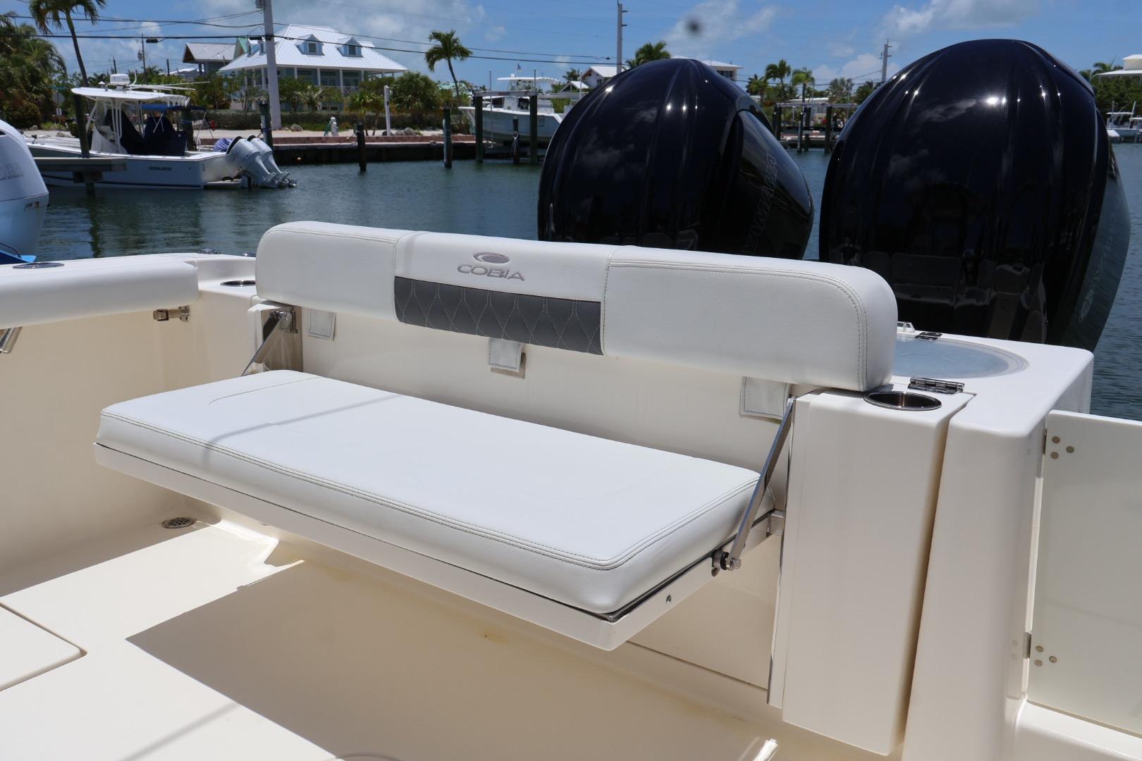 2022 Cobia 301 Center Console boat with white seating and dual engines.