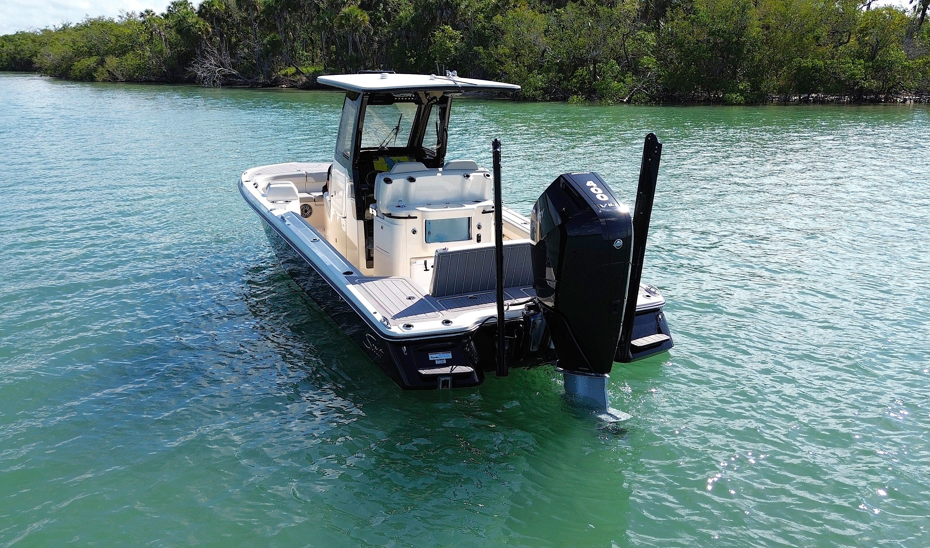 A 2024 Scout 281 XSS boat on calm water, surrounded by green vegetation.