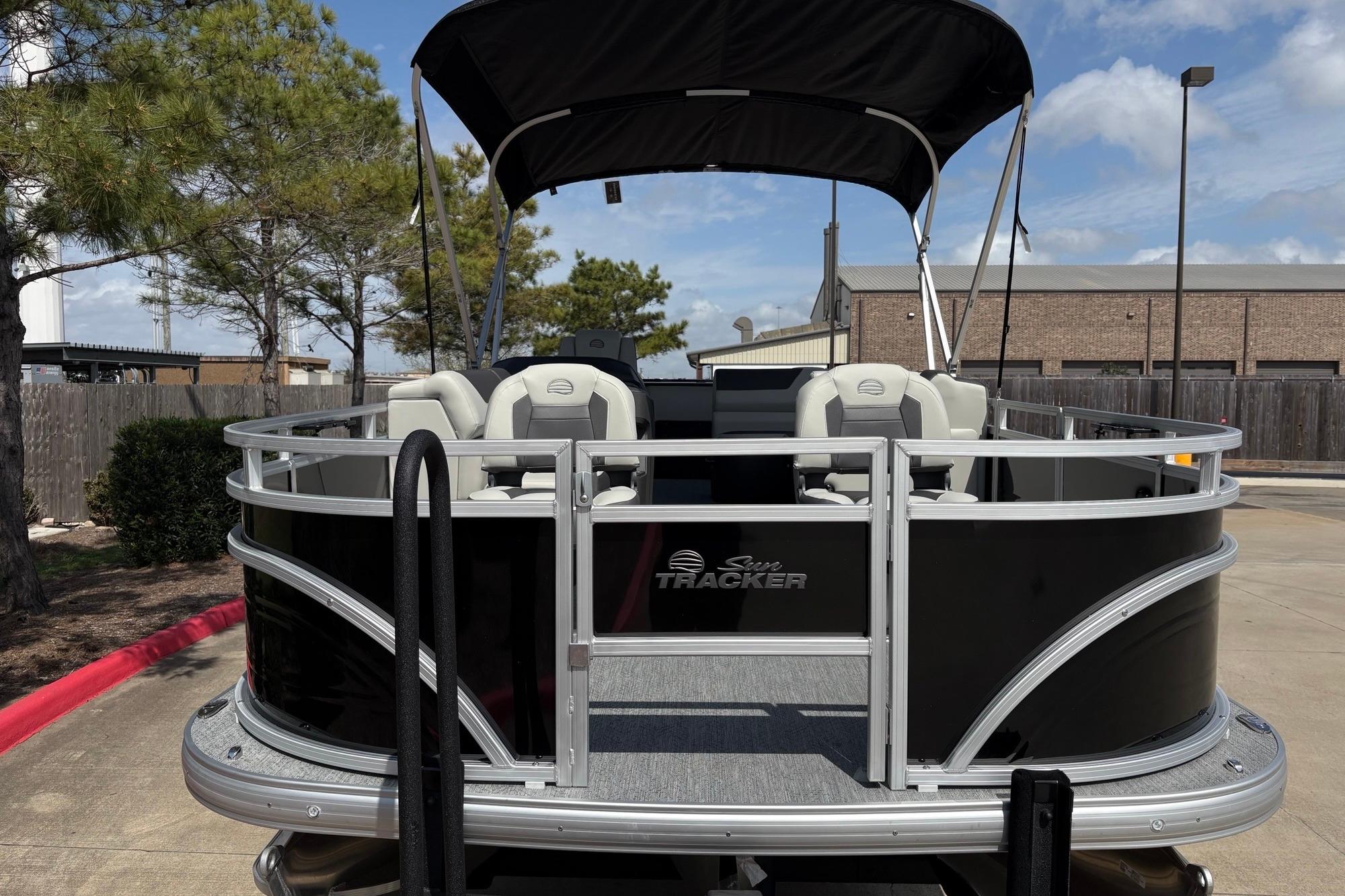 2026 Sun Tracker Fishin' Barge 22 XP3 pontoon boat with canopy, parked outdoors.